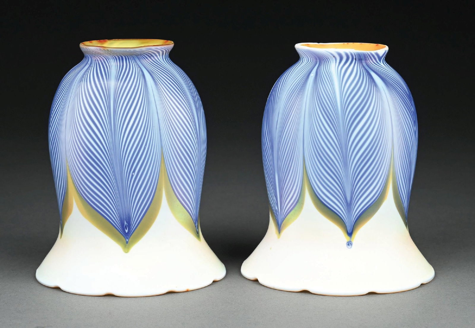 PAIR OF QUEZAL BLUE PULLED FEATHER TULIP SHADES: A wonderful pair of tulip shades by Quezal. Each tulip-formed shade stands 5-1/2" tall, and features a iridescent white background with blue pulled feather motif. Both shades are free of cracks or chi