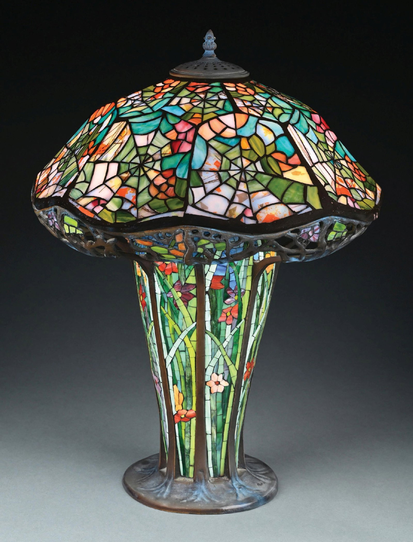 TIFFANY-STYLE COBWEB LEADED GLASS TABLE LAMP W/ BASE: A lovely example of a reproduction of the Tiffany Studios Cobweb leaded glass table lamp. The leaded glass shade has a clamshell form with cobweb motif in multicolored glass. The shade sits on a