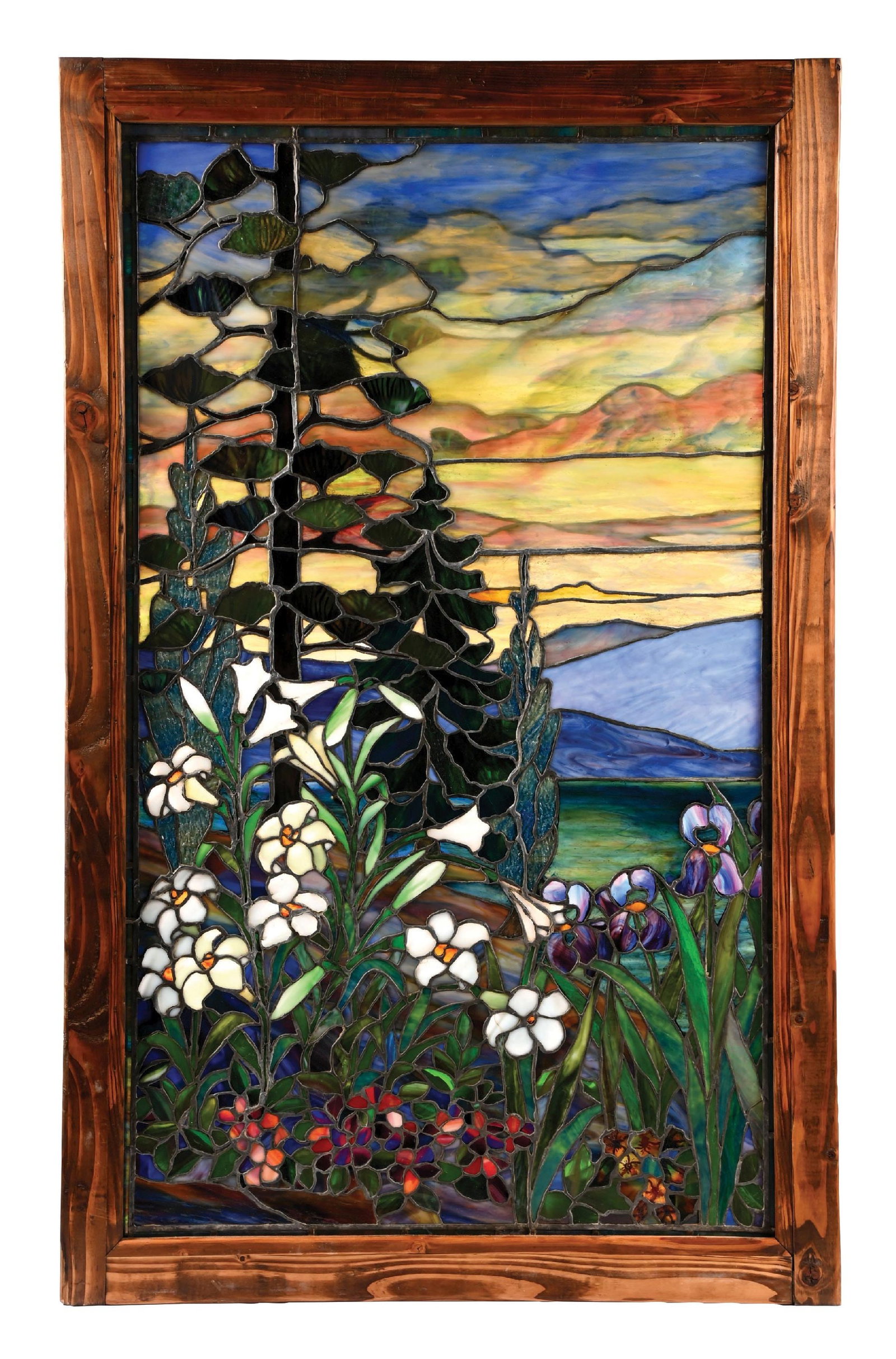 BEAUTIFUL FLORAL LANDSCAPE STAINED GLASS WINDOW: A beautiful early 20th century leaded and stained glass window attributed to Tiffany Studios. The 54" tall window features a landscape scene with blue and yellow-streaked skies and purple-streaked