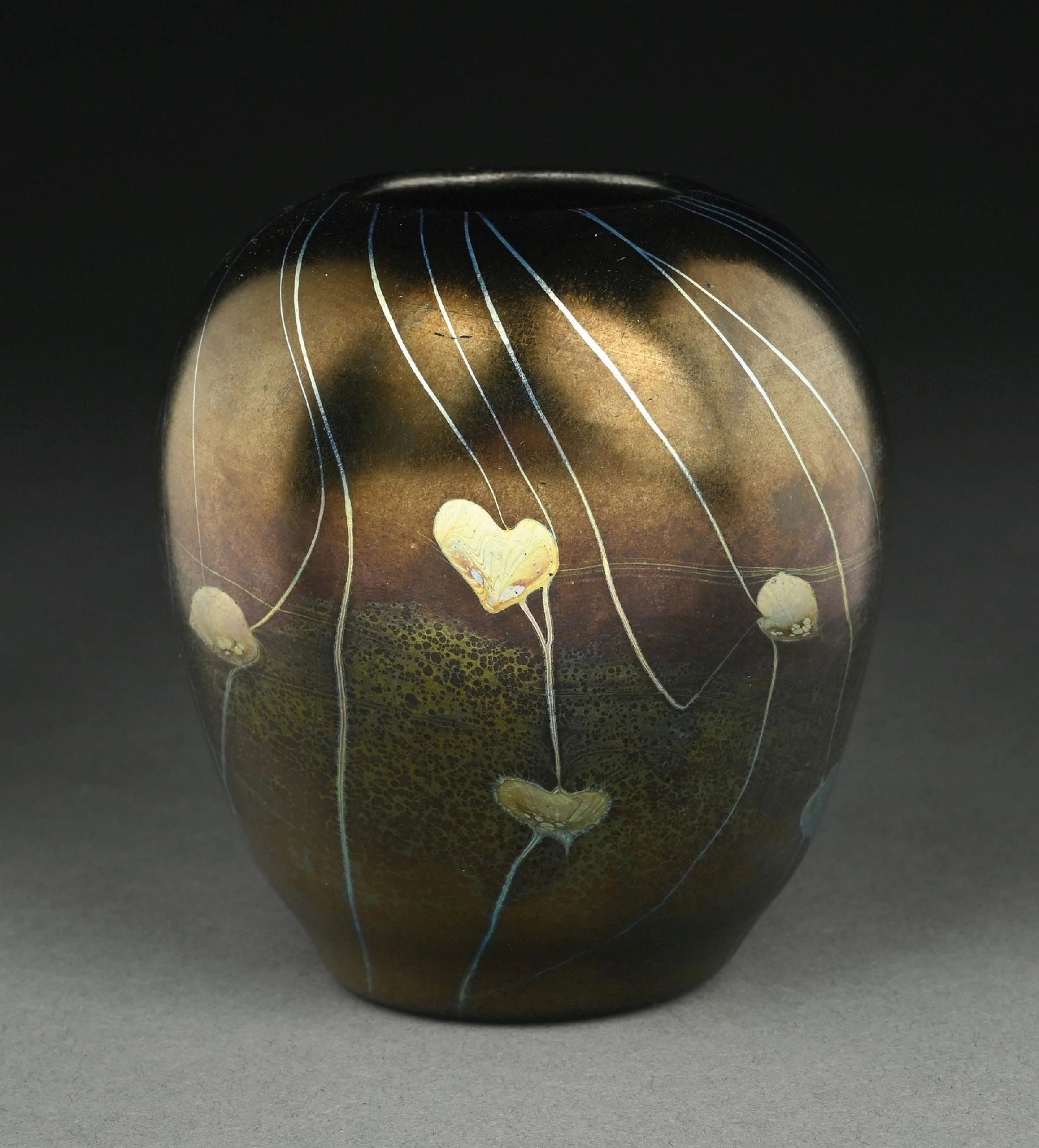 RARE TIFFANY STUDIOS BLACK LEAF & VINE VASE: A beautiful and rare black favrile glass vase by Tiffany Studios. The 4-1/2" tall vase features a black background with iridescence throughout. The vase is further decorated with an iridescent leaf an