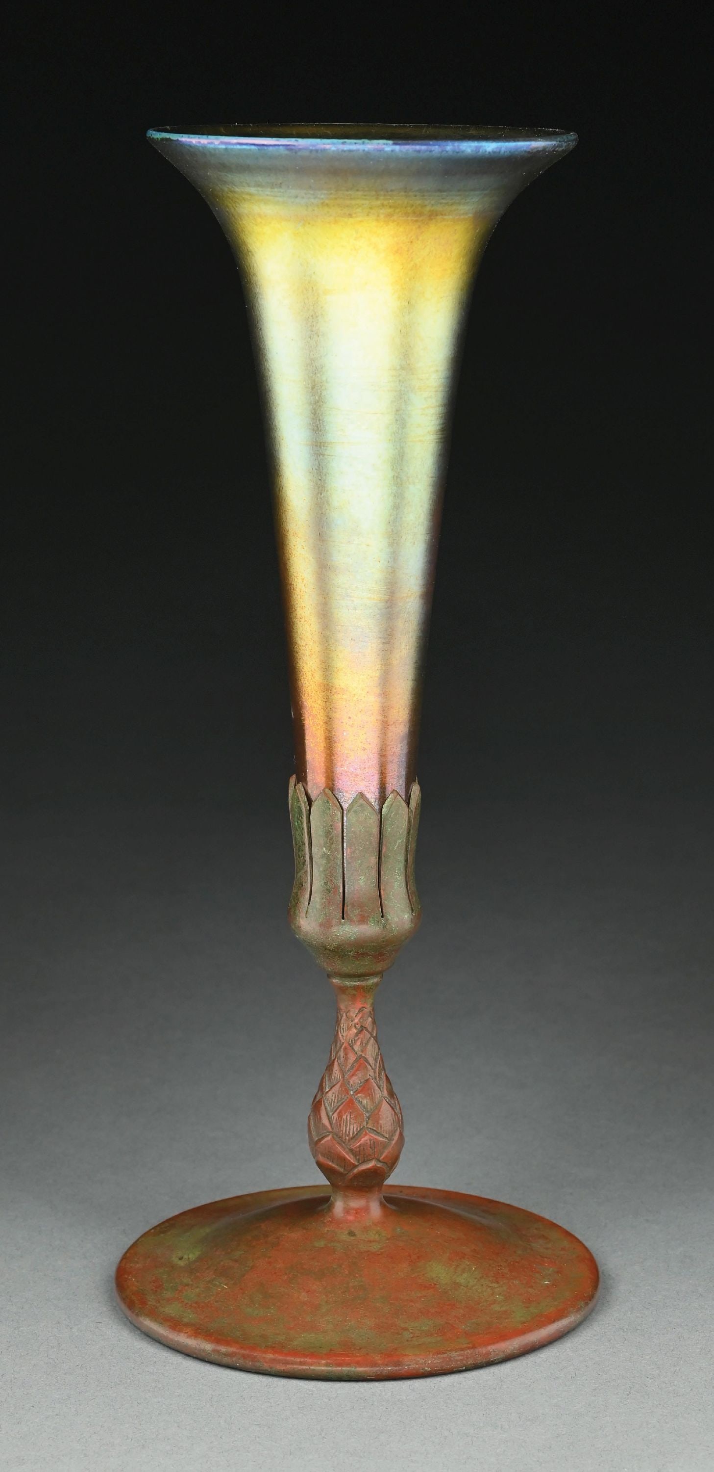 TIFFANY STUDIOS FAVRILE GLASS VASE WITH BRONZE VASE: A beautiful glass vase with bronze base by Tiffany Studios. The 8" tall glass vase has trumpet form and composed of iridescent gold glass. Signed around the insert "LCT Favrile". The shade sits on a p