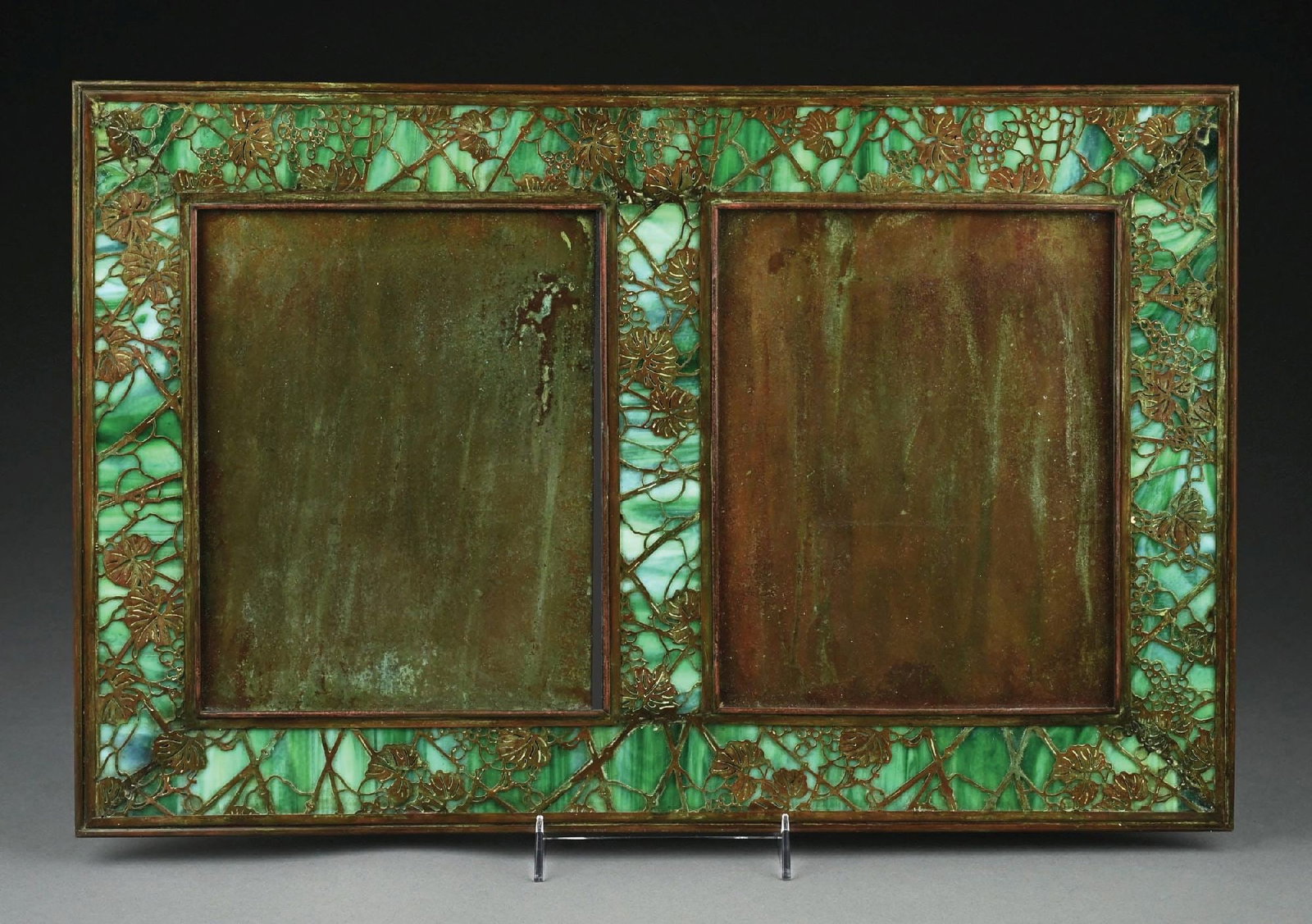 TIFFANY STUDIOS BRONZE AND GREEN/WHITE FAVRILE GLASS DOUBLE PICTURE FRAME: Rectangular frame with green and white stained glass panels and bronze floral overlay, includes two portraits openings. Condition: (Very Good). Dimensions: 22 - 3/4" x 14 - 3/4".