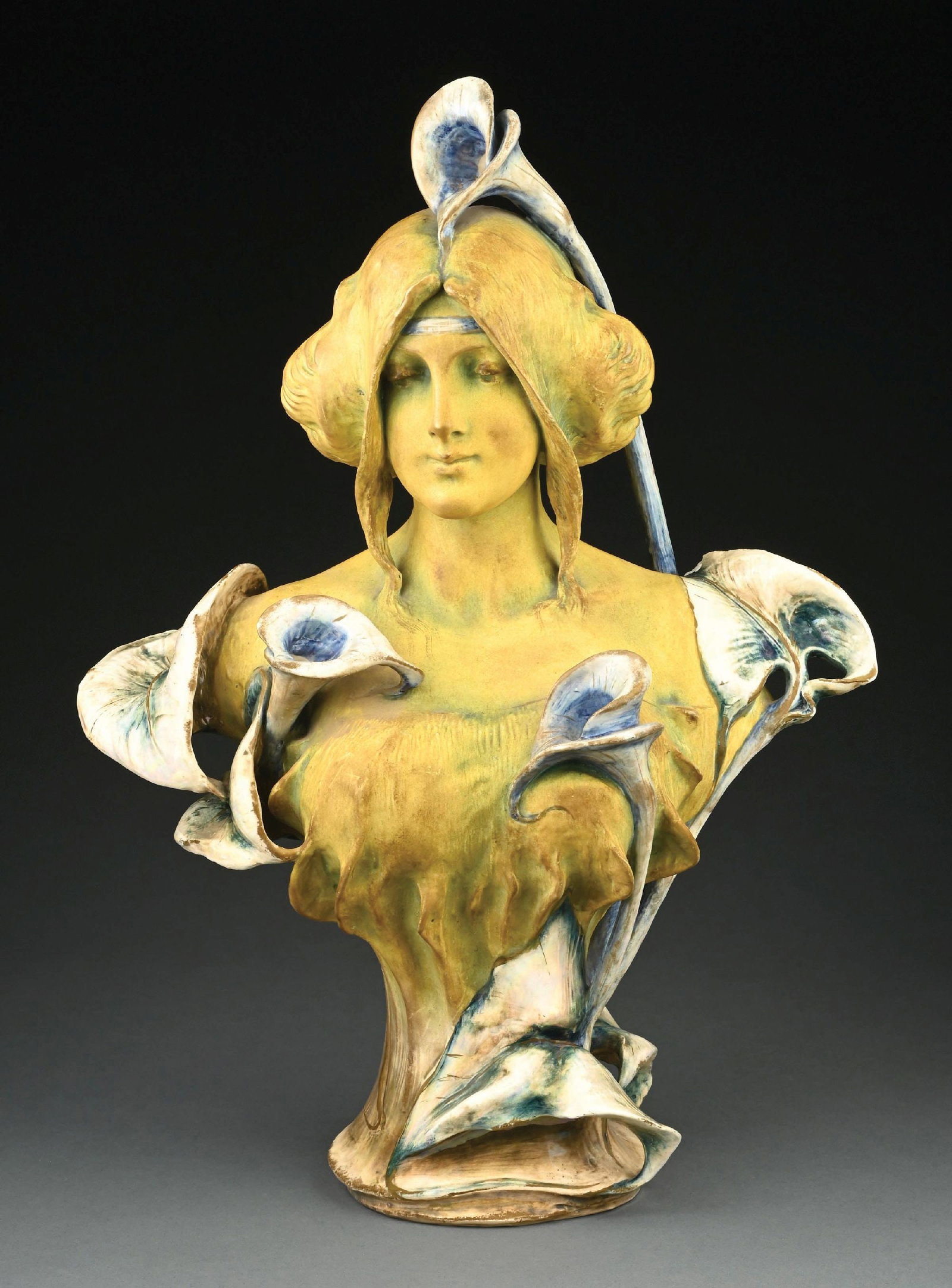 EXTREMELY RARE AMPHORA BUST DESIGNED BY PAUL DACHSEL: Highly stylized bust of a young woman with headband embraced by flowering Cala Lilies. Exquisitely modeled and detailed with high-fired and matte glazing. This model is not illustrated in Amphora
