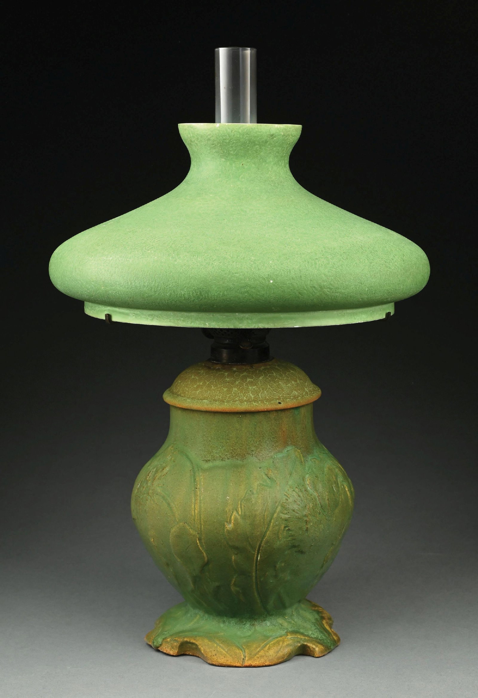 ROOKWOOD OIL LAMP WITH MOSSERINE SHADE: A lovely floral motif oil lamp by Rookwood. The 10" tall base has a beautiful green matte glaze with floral motif standing in relief. The vase is in excellent condition, with one rough area on the