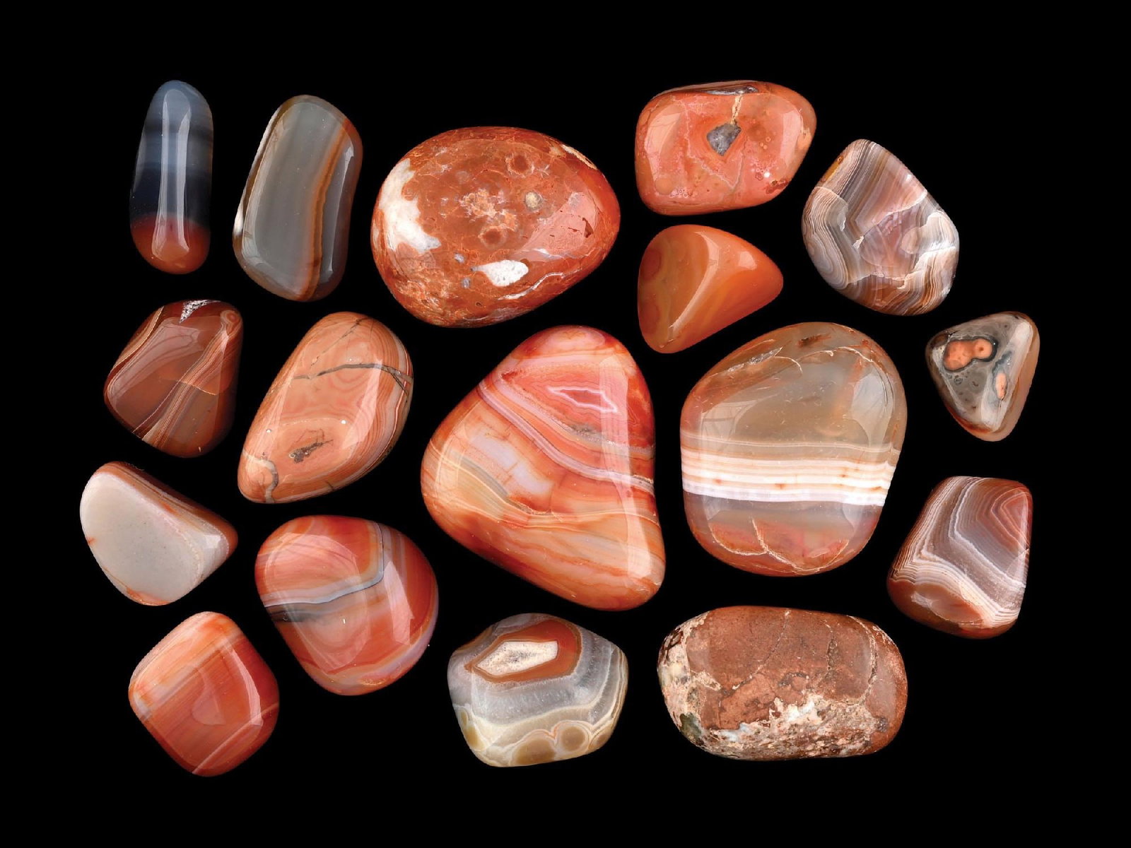 LARGE COLLECTION OF RED BANDED AGATE: A collection of seventeen polished banded agate and carnelian stone tumbles, including examples with fortification agate patterns. Commonly sourced from Brazil, Mexico, and Madagascar, these specimens