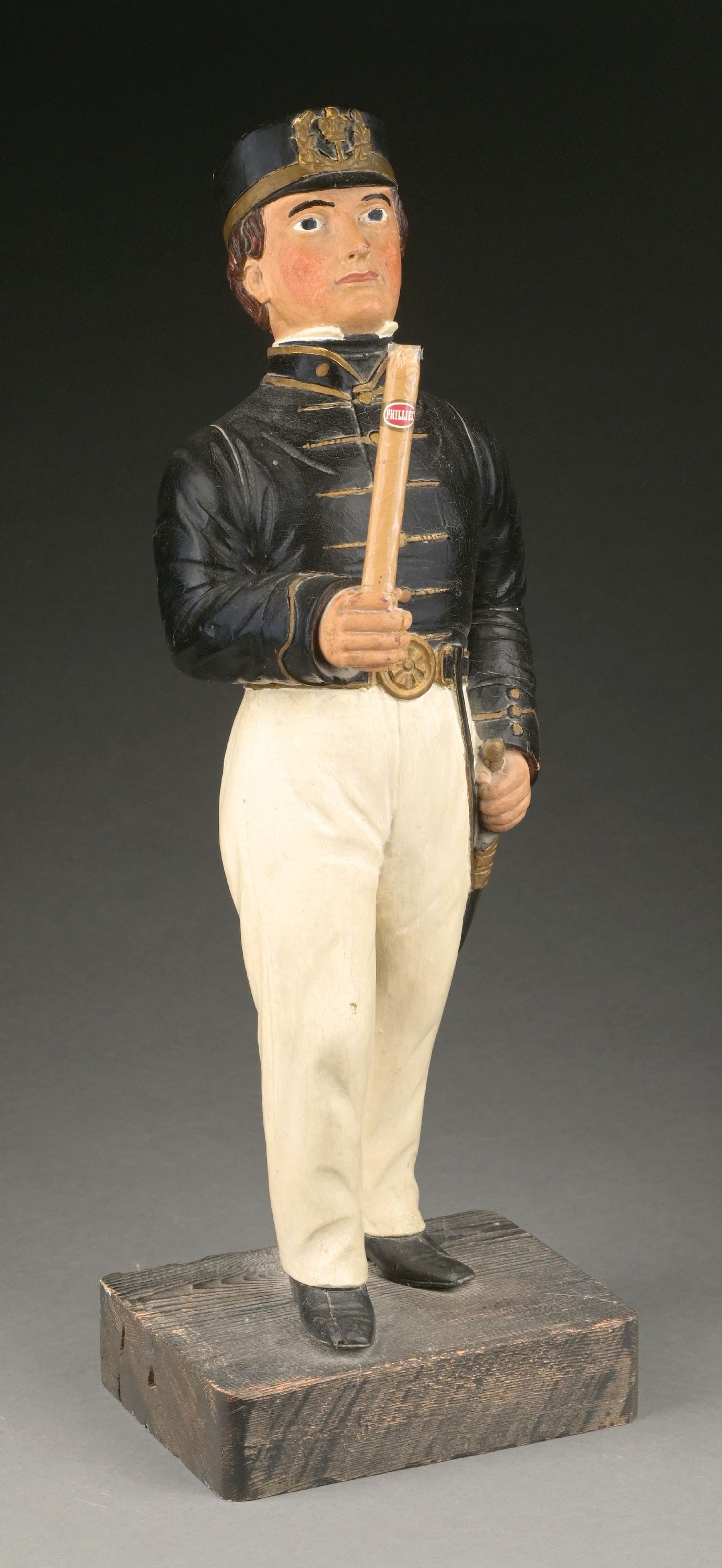 WOODEN NAVEL MAN HOLDING CIGAR FIGURE: Wooden carving of a man in uniform. Hand is clasped with a hole in it to hold, in this case, a cigar. Some minor wear throughout. Wonderful carving. Condition: (Very Good). Dimensions: 10" x 8" x 29".