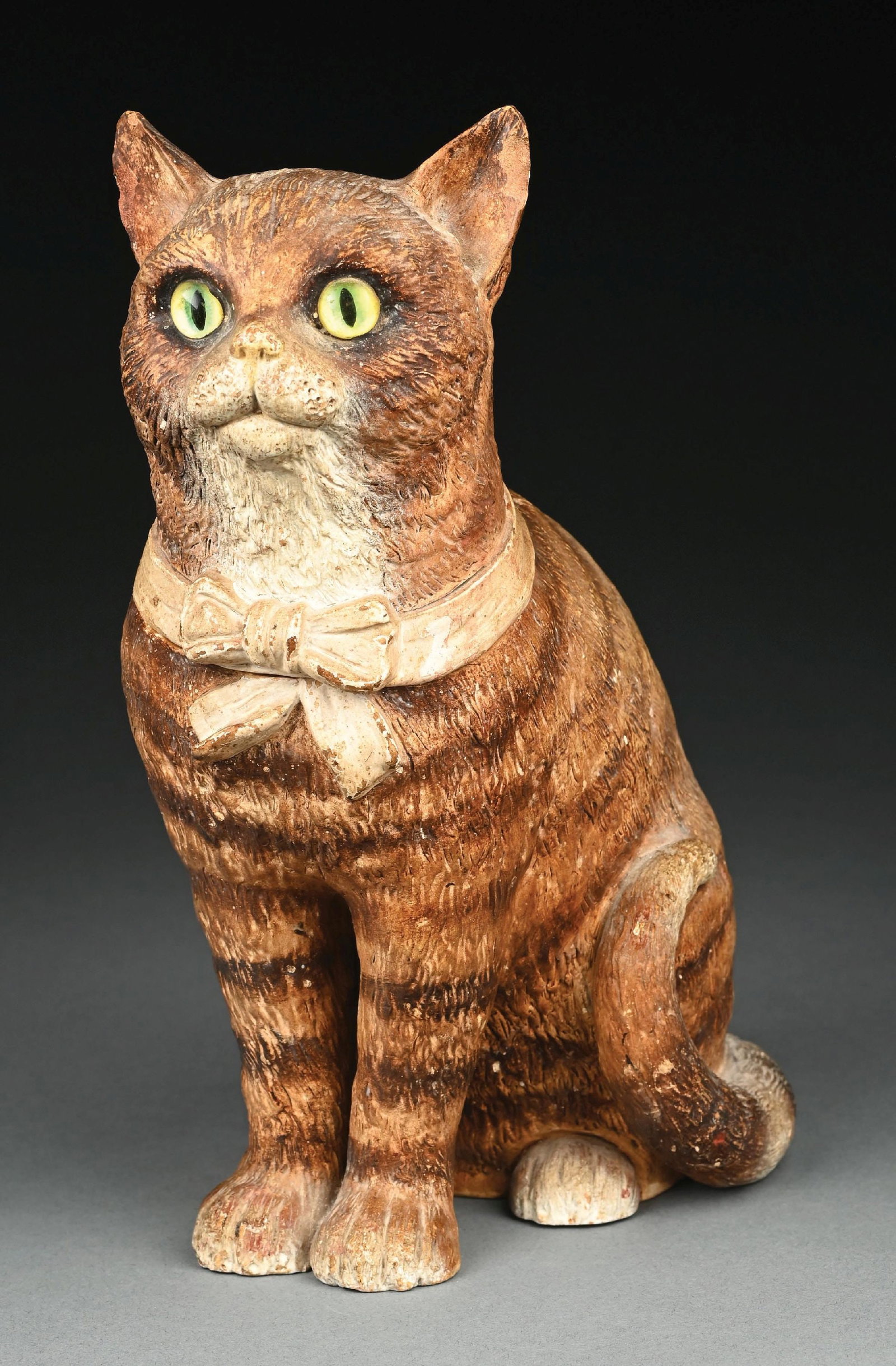 BERNARD BLOCK CAT WITH GLASS EYES TOBACCO HUMIDOR/JAR: C. 1890-1910. A Bernard Bloch figural cat tobacco jar featuring a seated tabby cat with glass inset green eyes and a molded bow collar. The cat is rendered in hand-painted ceramic with realistic fur t