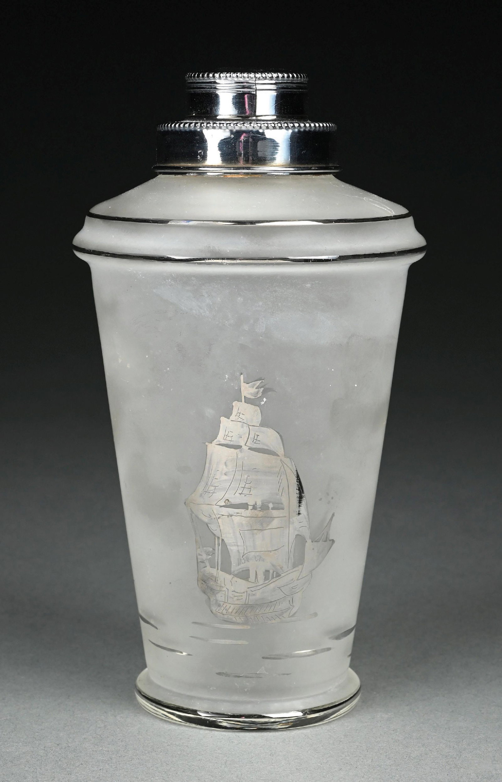 VINTAGE FROSTED GLASS TAPERED COCKTAIL SHAKER: C. 1940s-1960s. A vintage frosted glass cocktail shaker featuring an etched sailing ship motif. The cylindrical frosted glass body is decorated with a detailed tall-mast sailing vessel. The shaker is