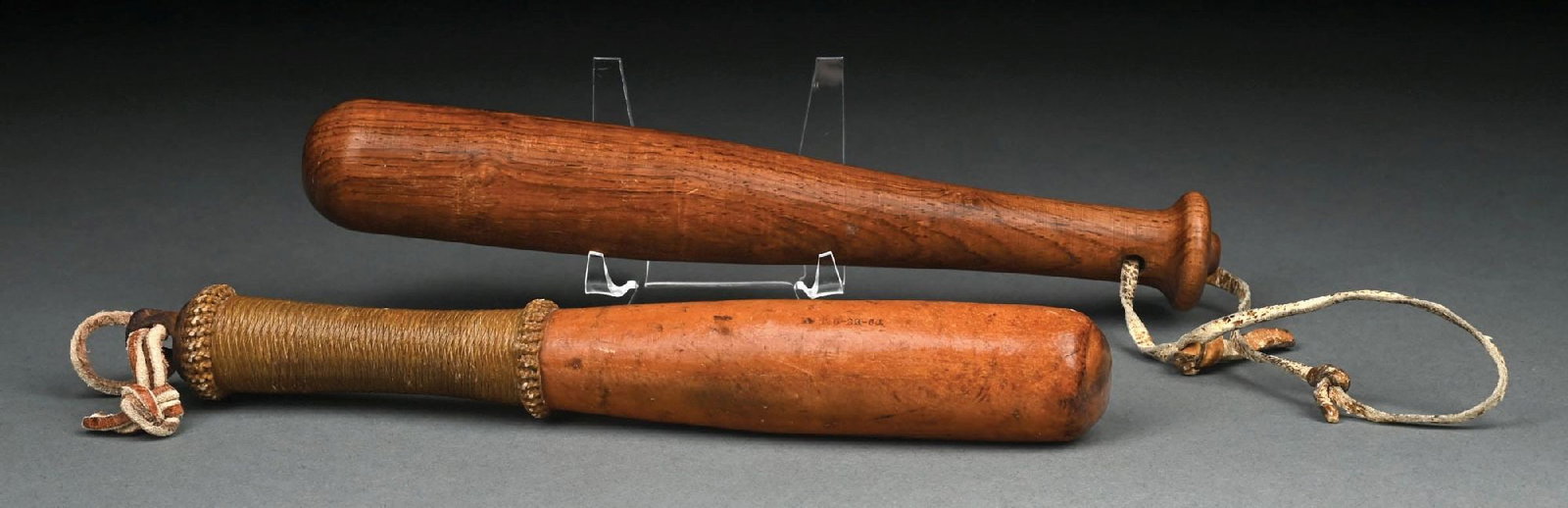 COLLECTION OF 2: BILLY CLUBS: (A) C. 1880s-1920s. A 9 - 1/4" law enforcement wooden Billy club featuring a rope or leather-wrapped grip and leather wrist strap. The club displays a well-worn patina consistent with age and use.