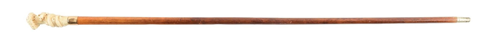 ANTIQUE WALKING STICK W/ FIGURAL SNAKE CARVED IVORY HANDLE AND WOOD SHAFT: C. 1890–1915. Figural walking cane with a carved ivory pommel in the form of a coiled snake on a textured ground with a flat button-style cap. The snake shows defined carving. Mounted to a