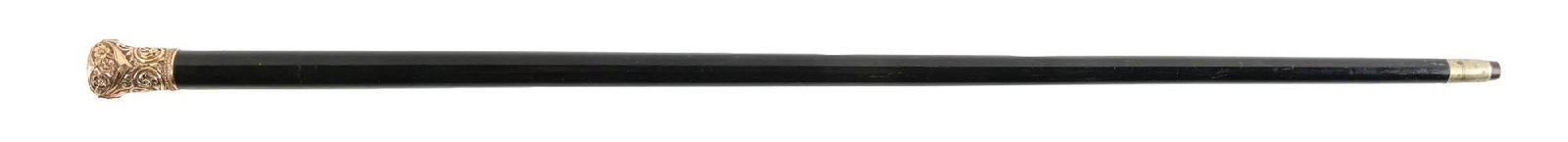 PRESENTATION WALKING STICK W/ GOLD-FILLED ORNATE KNOB AND EBONY SHAFT: C. 1890–1910. Decorative gilt metal repoussé handled walking cane featuring raised floral and scrollwork ornamentation. The domed top is engraved “A.M. Gutchman — From T.