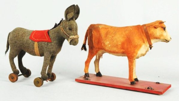 Lot of 2: Early Animal on Platform Toys.: Unmarked but probably German. Includes one composition cow on wooden platform with iron wheels and one straw-filled donkey on wooden wheels. Cow is missing one udder, has a broken horn on right side,
