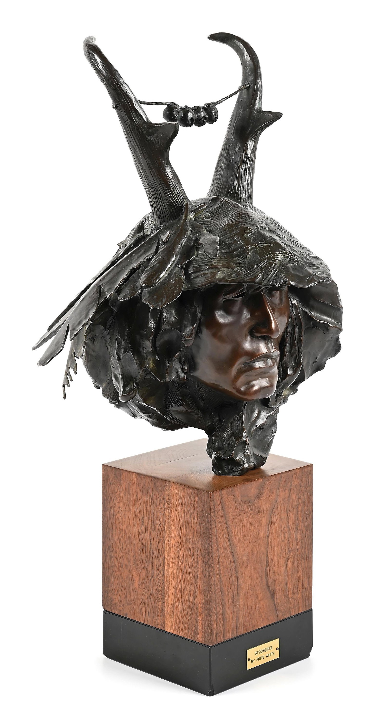 FRITZ WHITE (AMERICAN, 1930-2010): Wyoming bronze sculpture 6" L x 6" W x 16-1/2" H with stand: 25" H numbered 19/253 Bronze sculpture of an indigenous face wearing a pronghorn antelope headdress. Dimensions: 6" x 6" x 25".