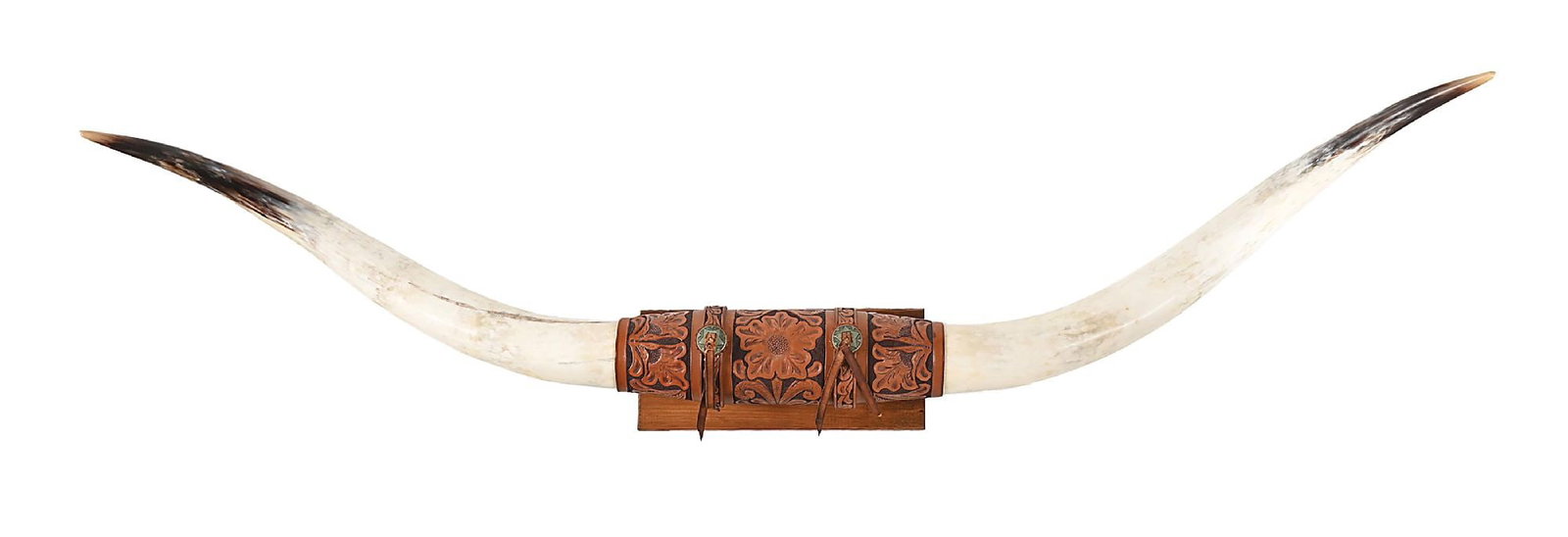 A PAIR OF STEER HORNS: Contemporary. With central leatherwork and floral pattern, highlighted with straps of leather extending from a pair of conchos. This is not a standard shippable item and will require 3rd party shippin
