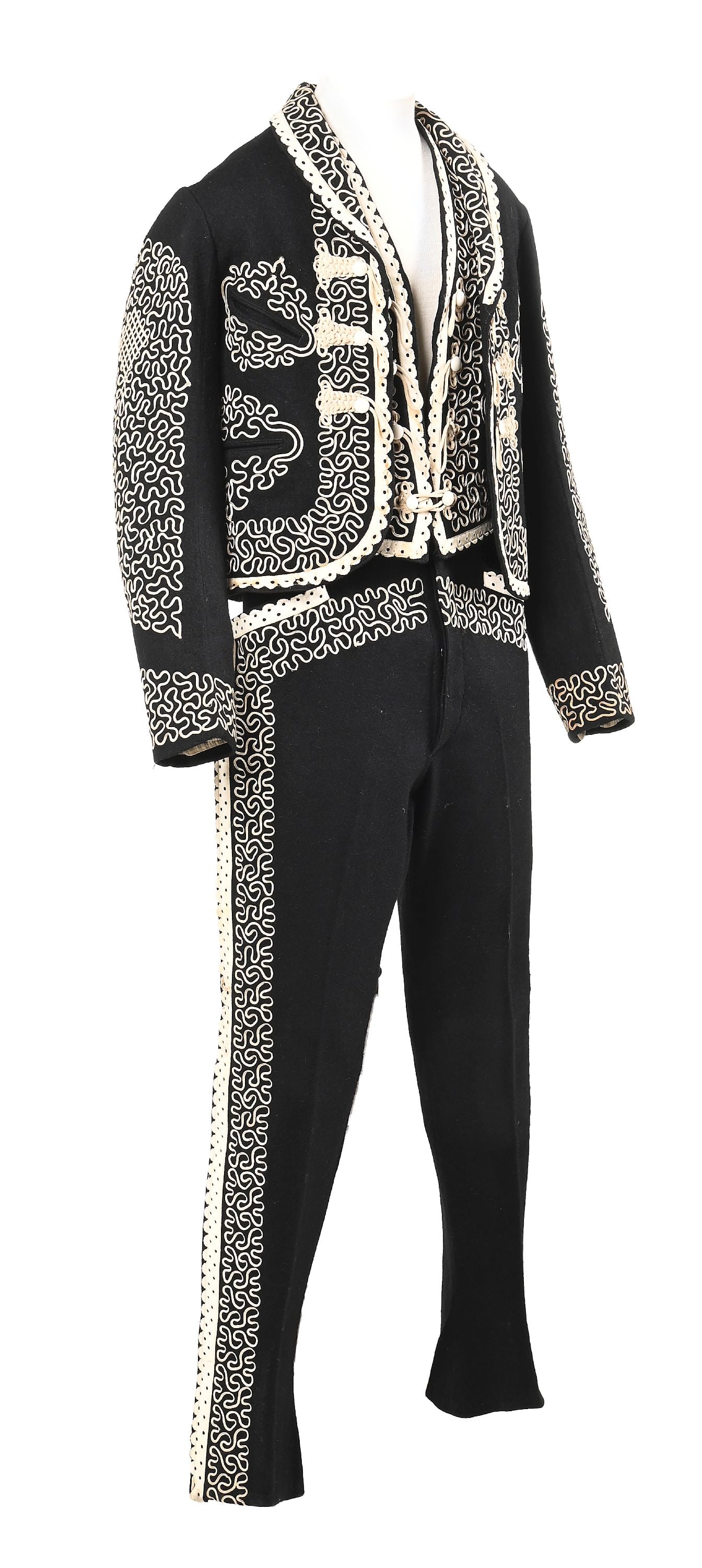 MARIACHI PANT SUIT: Mid-20th century. With extensive curvolinear embroidery and leather trim adorning the sides of the jacket vest and pants. Colors: black, cream Jacket - 17" Width, 22 - 1/2" Length, 24 - 1/2" Sleeve