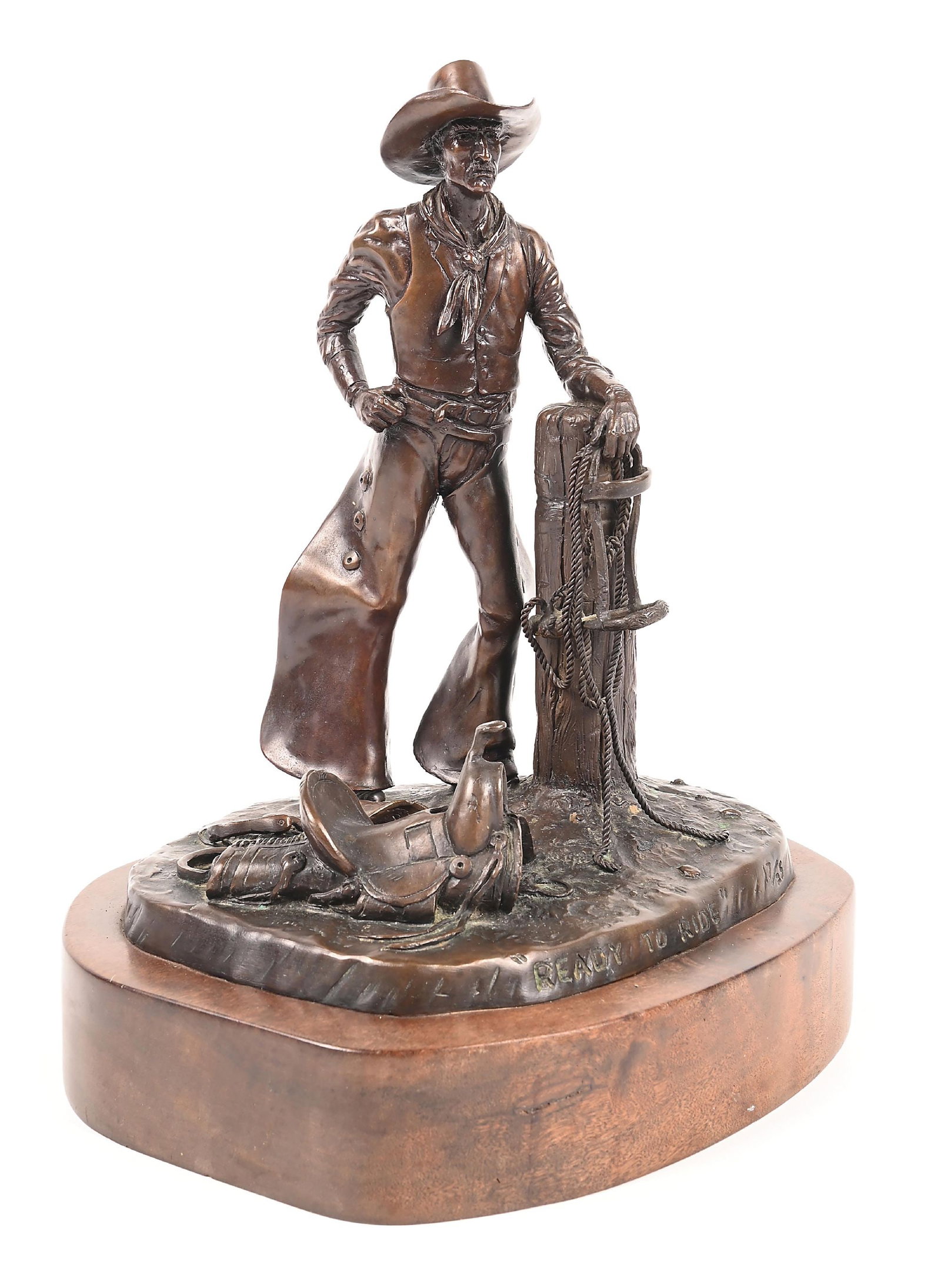 JIM STUCKENBERG (1943 -): Ready to Ride Bronze with dark brown patina with natural oxidation 7-1/2" x 6-1/4" x 9-1/2" Depicting a cowboy figure with a harness and the saddle at his foot Titled and numbered 17/25 on the front