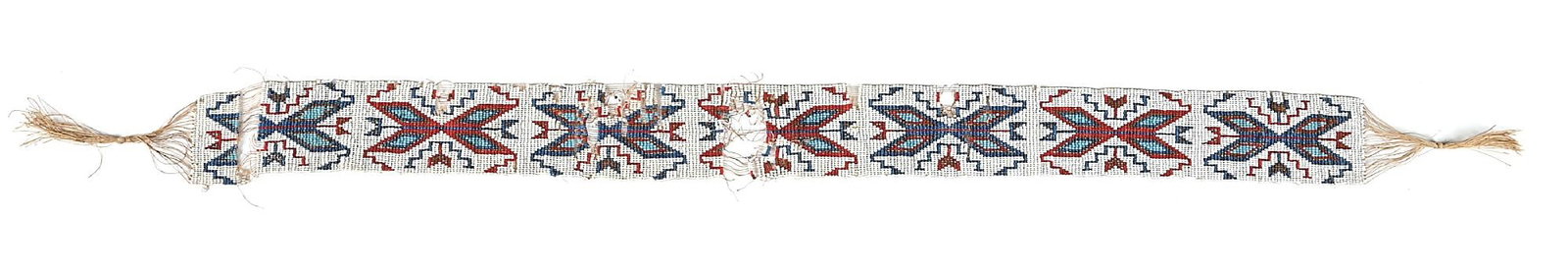 LOOM BEADED SASH: With a repeating geometric pattern. Condition: Several areas of bead loss. Colors: white, blue, red, light blue, metallic Provenance: Oral history from the consigner states that the sash was owned by