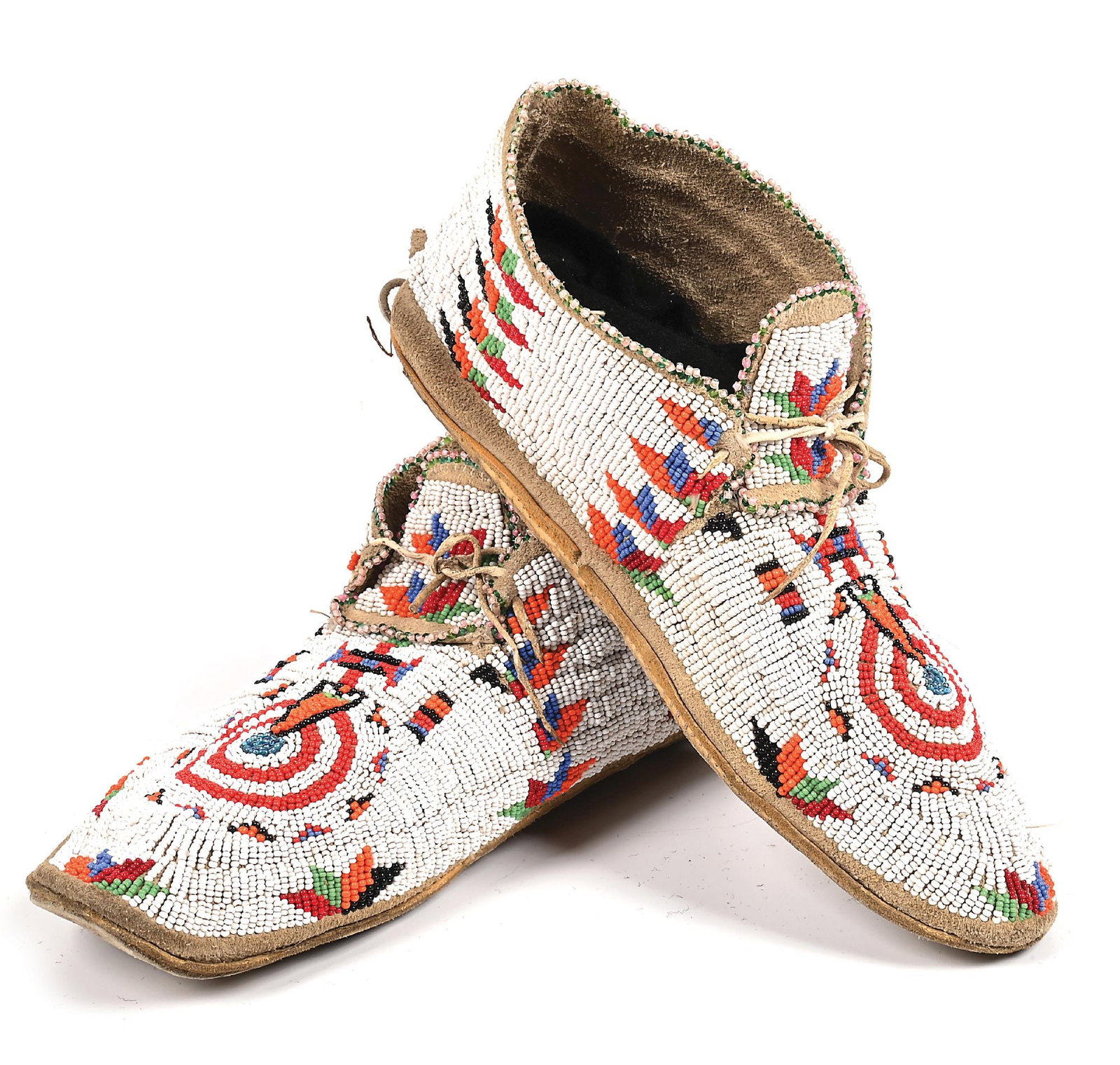 ARAPAHO BEADED MOCCASINS: Mid-20th century. With a central rosette pattern and vertical rows of floral leaf design. Parfleche soles. Colors: white, red, orange, blue, green, black Dimensions: 10" L.