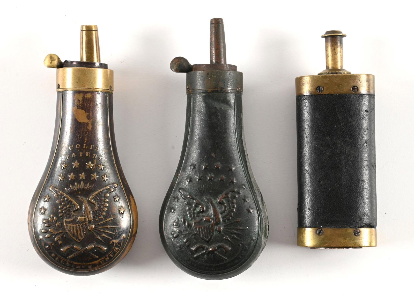 LOT OF 3: MID 19TH CENTURY POCKET REVOLVER POWDER FLASKS.: Lot includes two 3 3/4" Colt flasks. One is stamped Colts Patent and features two revolvers, eagle and stars (Riling #809). It is excellent in condition with some finish wear and no readily apparent d
