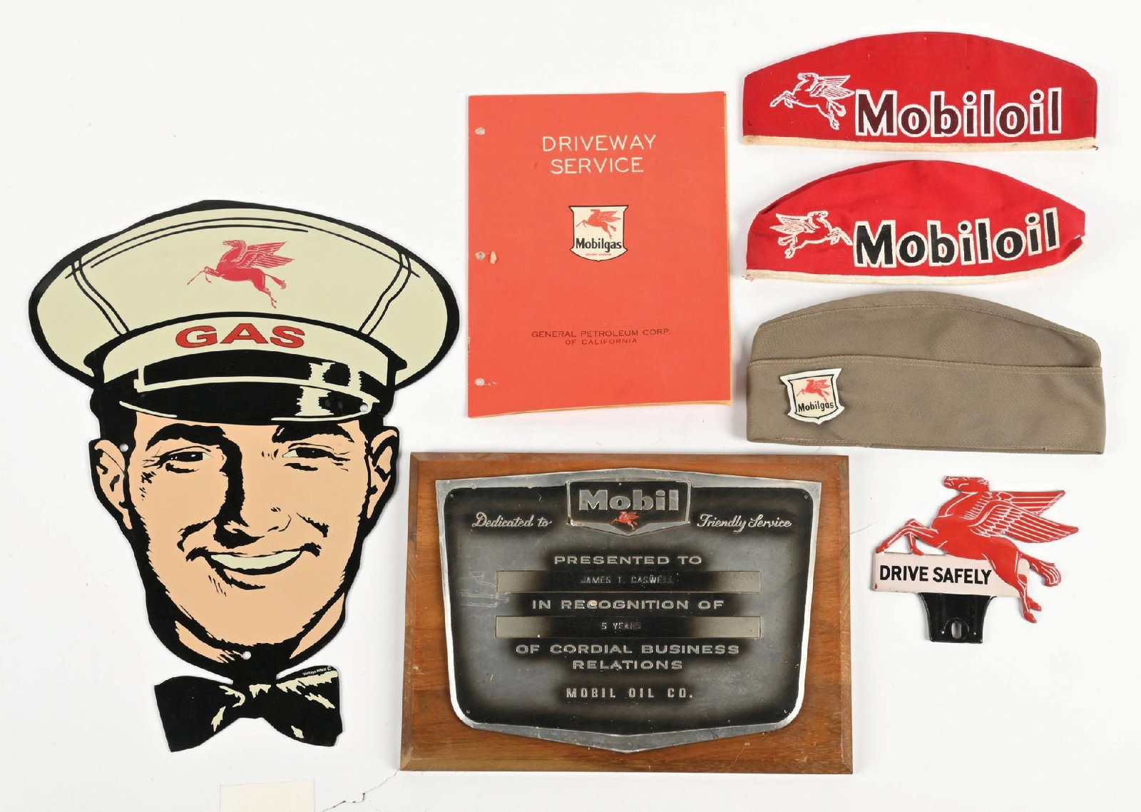 COLLECTION OF 7: MOBILGAS SERVICE STATION EPHEMERA: Collection Consists Of: Three Service Station Attendant Caps, Embossed Tin License Plate Topper, Mobil Business Relations Plaque, Driveway Service Catalog and Contemporary Service Station Attendant Si