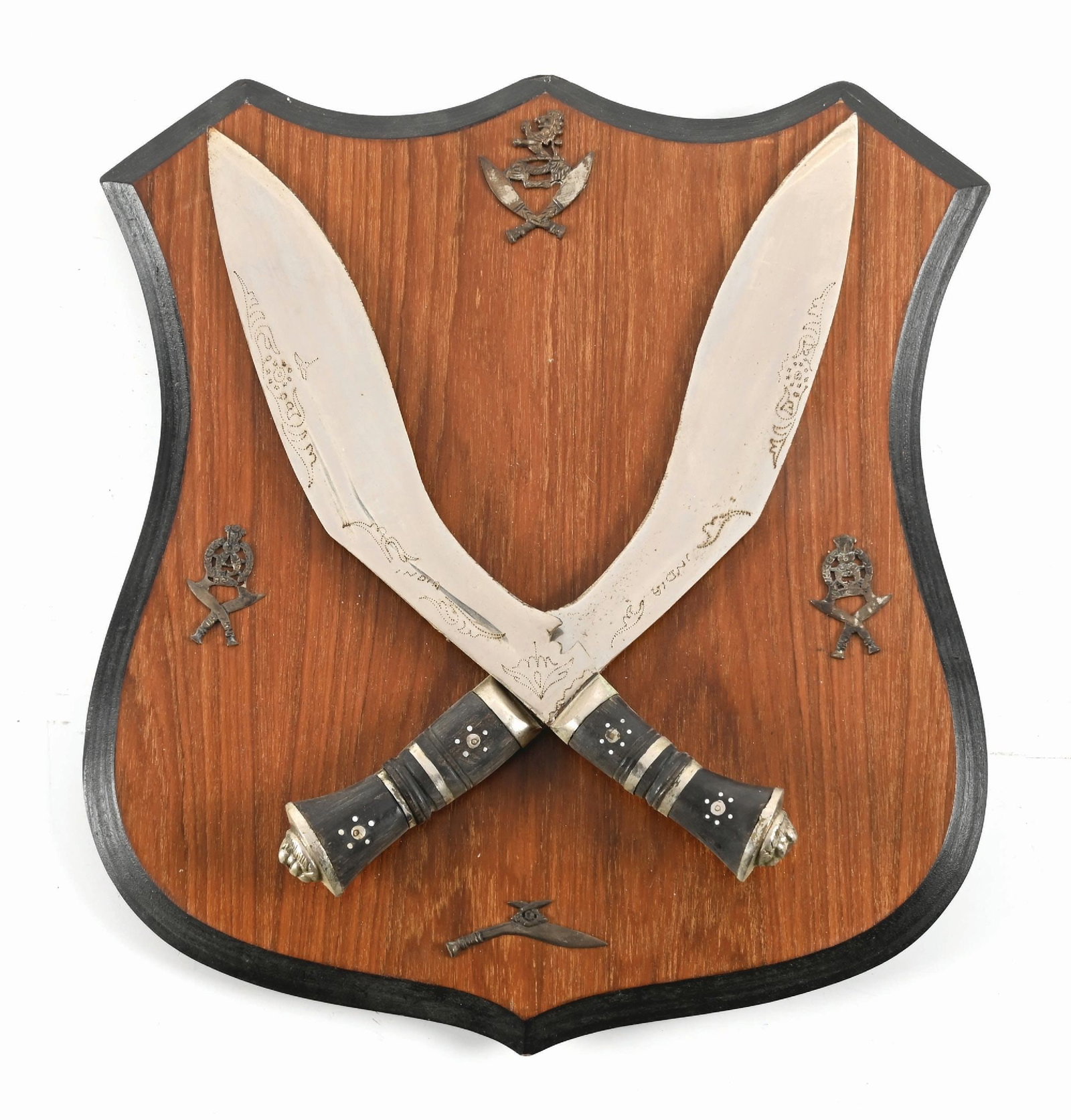 KUKRI KNIFE DISPLAY.: Two Kukri knives displayed in a wood shield. Blades exhibit dot engraved decorations with gray patina. CONDITION: Good. Blade Length: (BOTH) 12" Overall Length: (BOTH) 16"