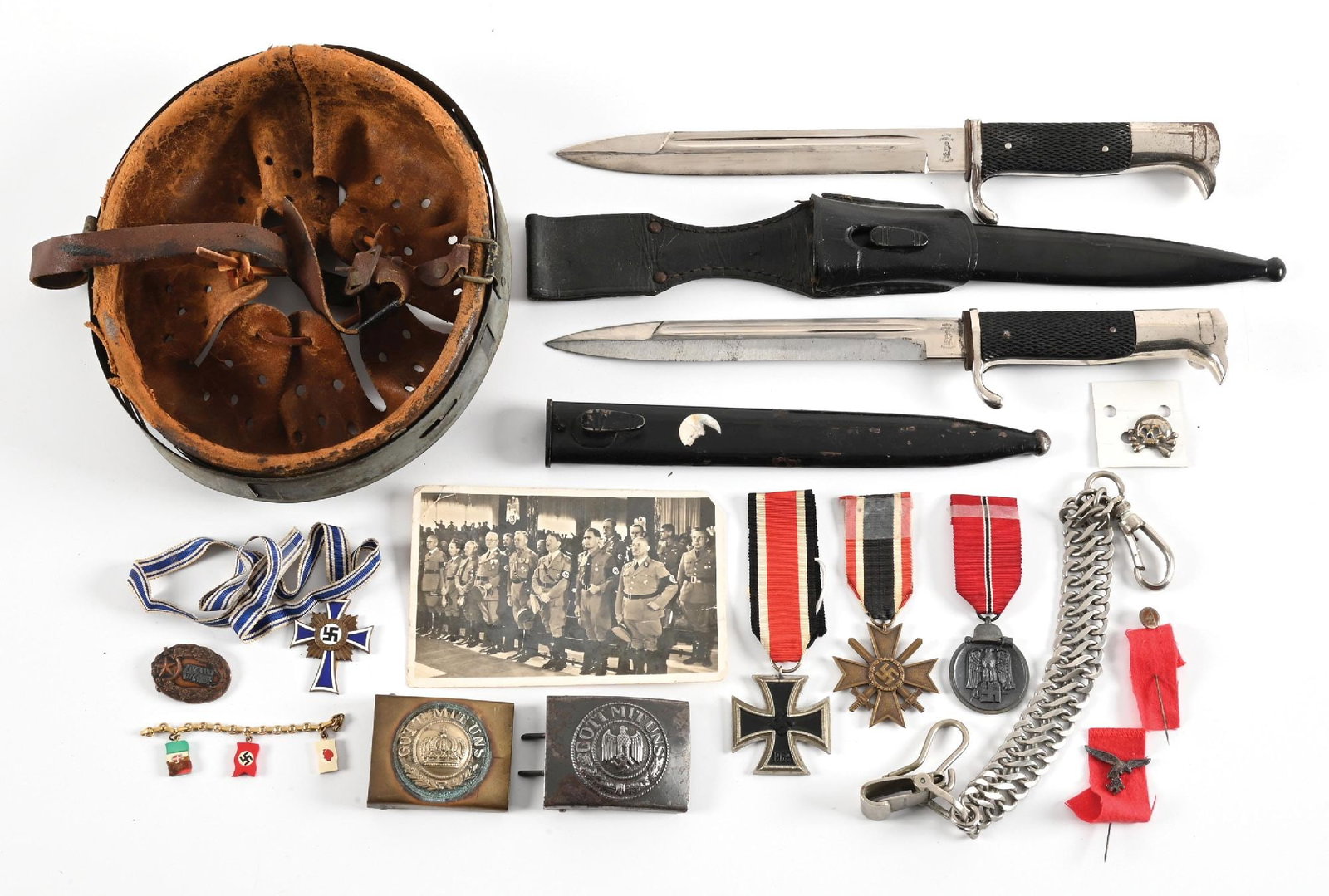 LOT OF GERMAN WWII MISCELLANEOUS BUCKLES, BAYONETS, MEDALS, INSIGNIA, AND HELMET LINER.: Lot contains German World War II miscellaneous items to include a helmet liner (size "57") in a size "64" zinc liner band which appears to be "1940" dated. Liner is heavily damaged with a very late th