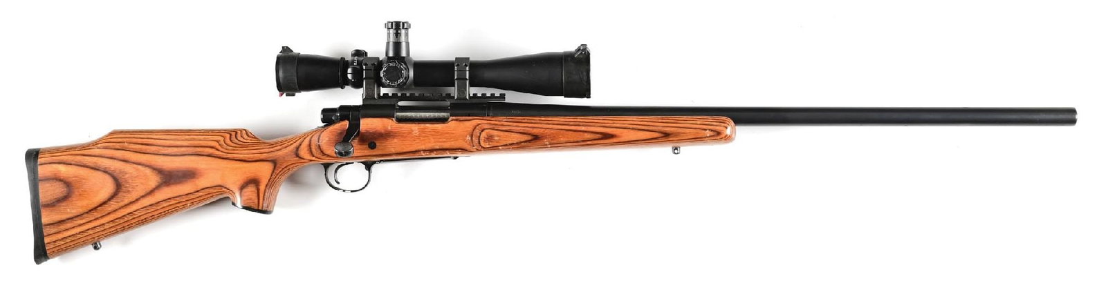 (M) REMINGTON MODEL 700 WITH LEUPOLD MARK 4 OPTIC: Short action rifle, features a heavy varmint taper barrel with blued finish. The Monte Carlo style stock is a wood laminate. The scope is a Leupold Mark 4 with a fixed 16x power. The reticle is a mild