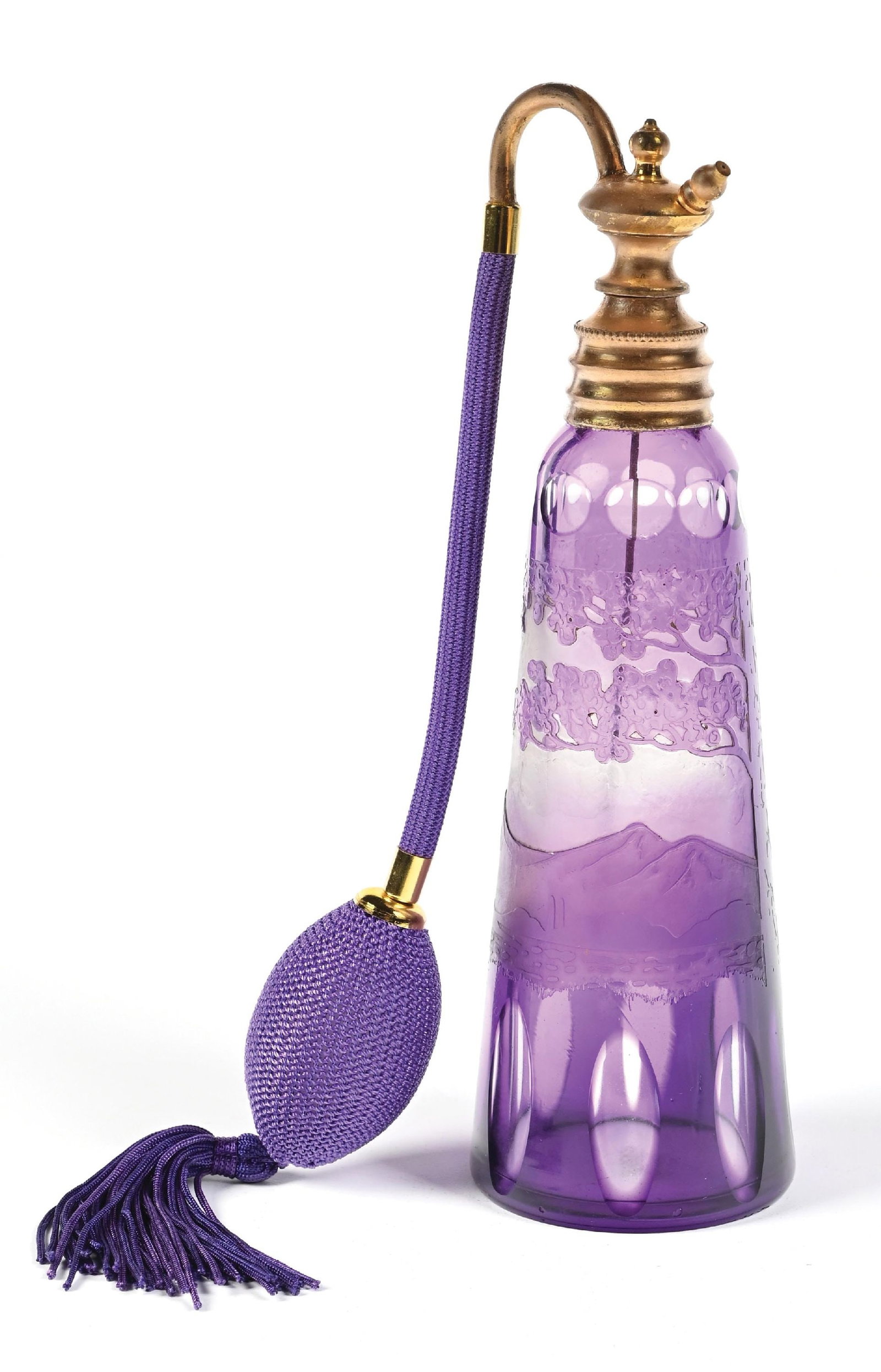 PURPLE CAMEO GLASS PERFUME WITH GOLD TONE TOP FEATURING A PATTERN OF HILLS AND TREES WITH ATOMIZER: C. 1900s. A wonderful purple perfume atomizer with a tapered cylindrical shape featuring a cameo glass scenic design of mountains and trees, as well as thumbprint and circular windows. The hardware at