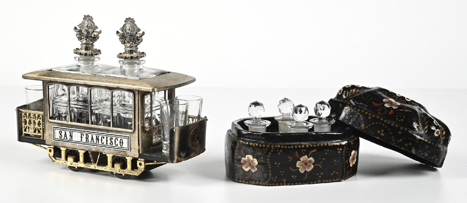 LOT OF 2: BLOOMINGDALE'S PERFUME CASKET & SAN FRANSISCO TROLLEY CAR DECANTER SET: C. 1900s. (A) A charming San Francisco decanter trolley with four shot glasses and two decanters. The decanters have rectangular faceting and silver-toned metal lion and shield shaped stoppers. The tr
