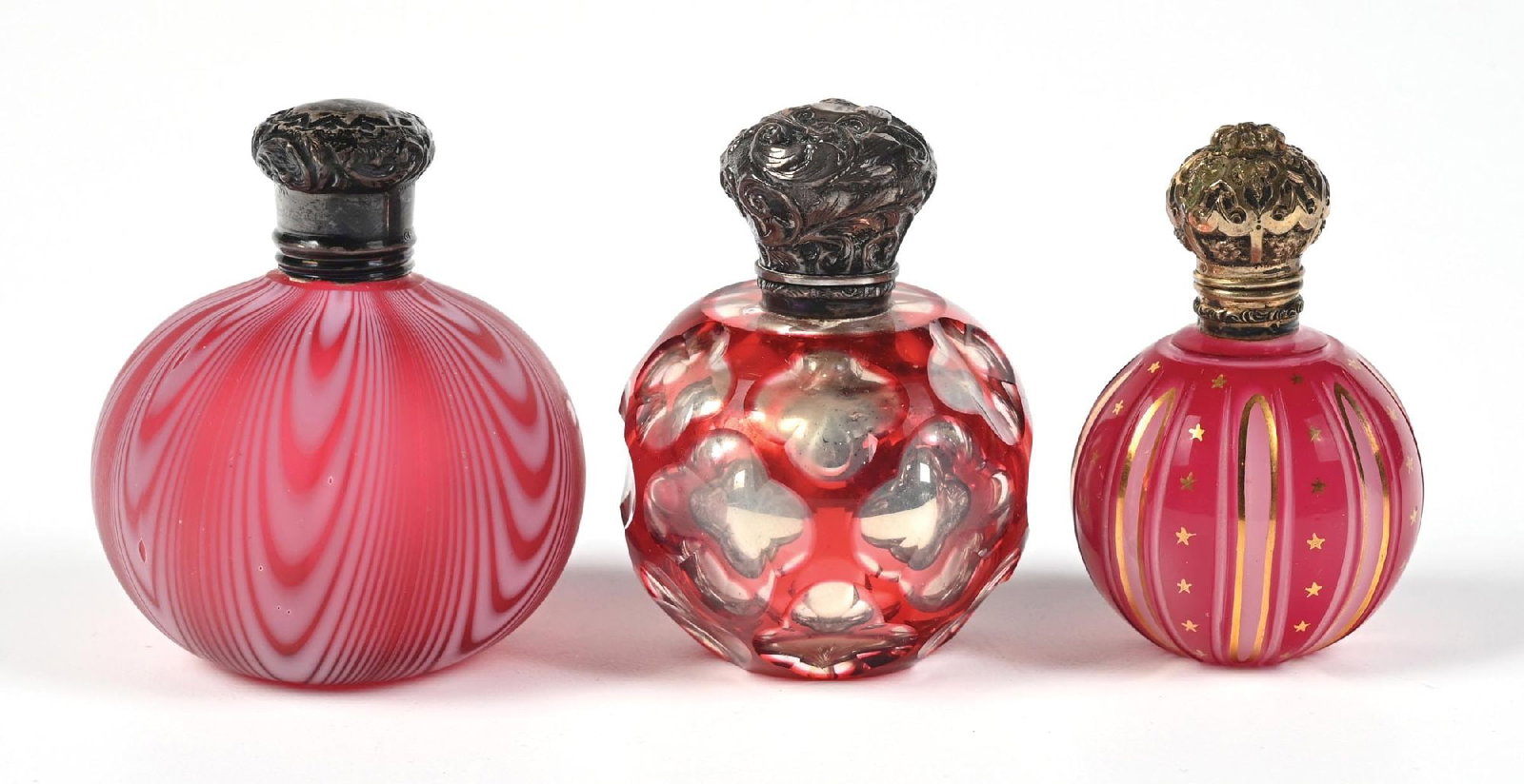 LOT OF 3: CRANBERRY GLASS PERFUME BOTTLES: C. 1870s-1900s. (A) A lovely signed "CS star FS" Saunders, Shepherd & Co. perfume with an ornate star-patterned silver lid. The perfume features a fascinating feathered or swirled pattern on a globula