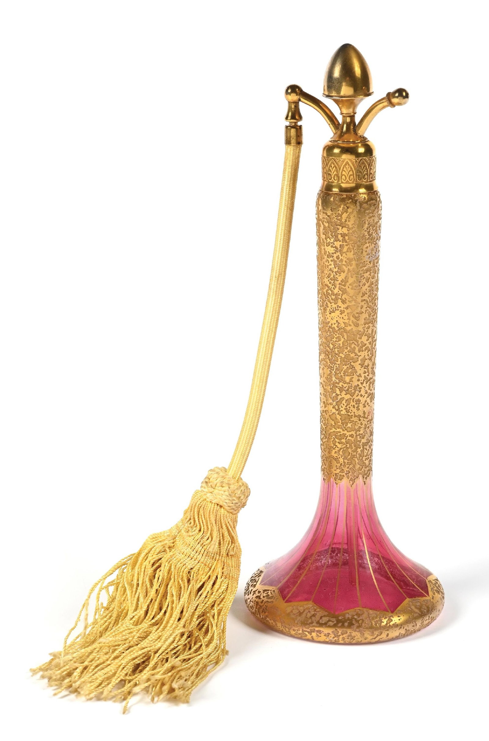 DEVILBISS GOLD AND CRANBERRY TALL PERFUME WITH ATOMIZER: C. 1920s. A beautiful Art Deco, signed DeVilbiss perfume atomizer featuring a gilded, chipped-ice-textured body over cranberry-colored glass, with a yellow tasseled atomizer puff. The perfume is in gr