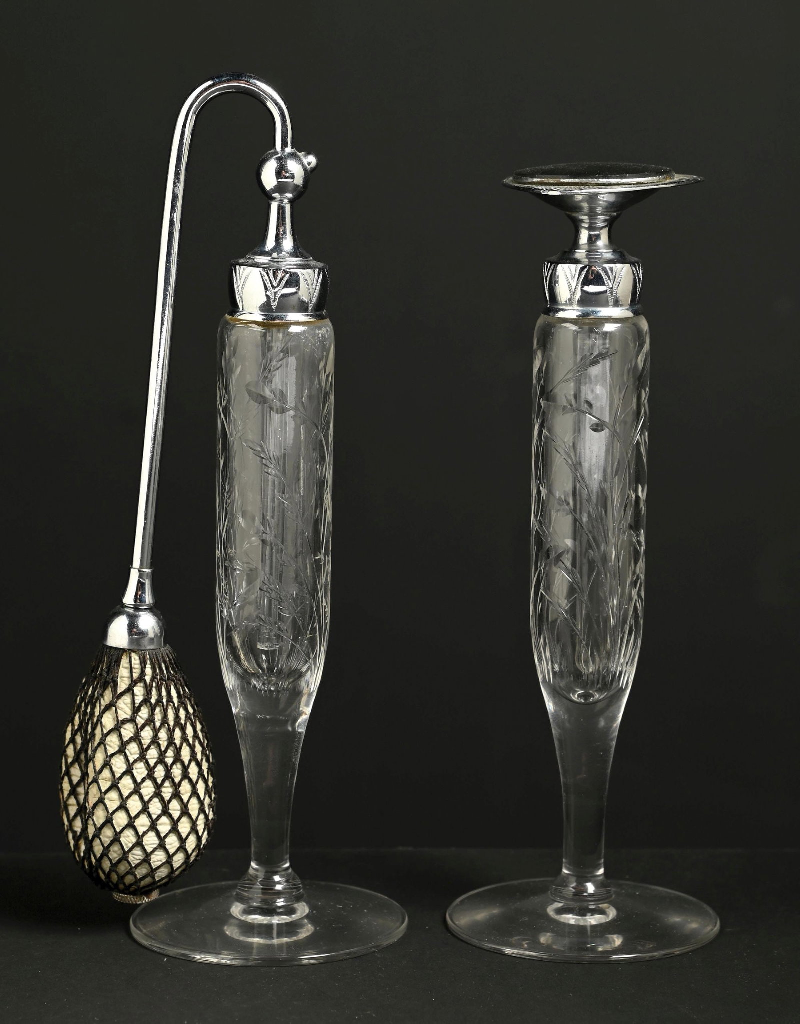LOT OF 2: DEVILBISS ETCHED GLASS ROCK CRYSTAL PERFUME BOTTLE SET: C. 1920s. A beautiful pair of DeVilbiss acid-etched glass perfume atomizers. The clear glass bodies feature etched floral designs, and the metal-chrome-toned hardware appears in great condition. The b