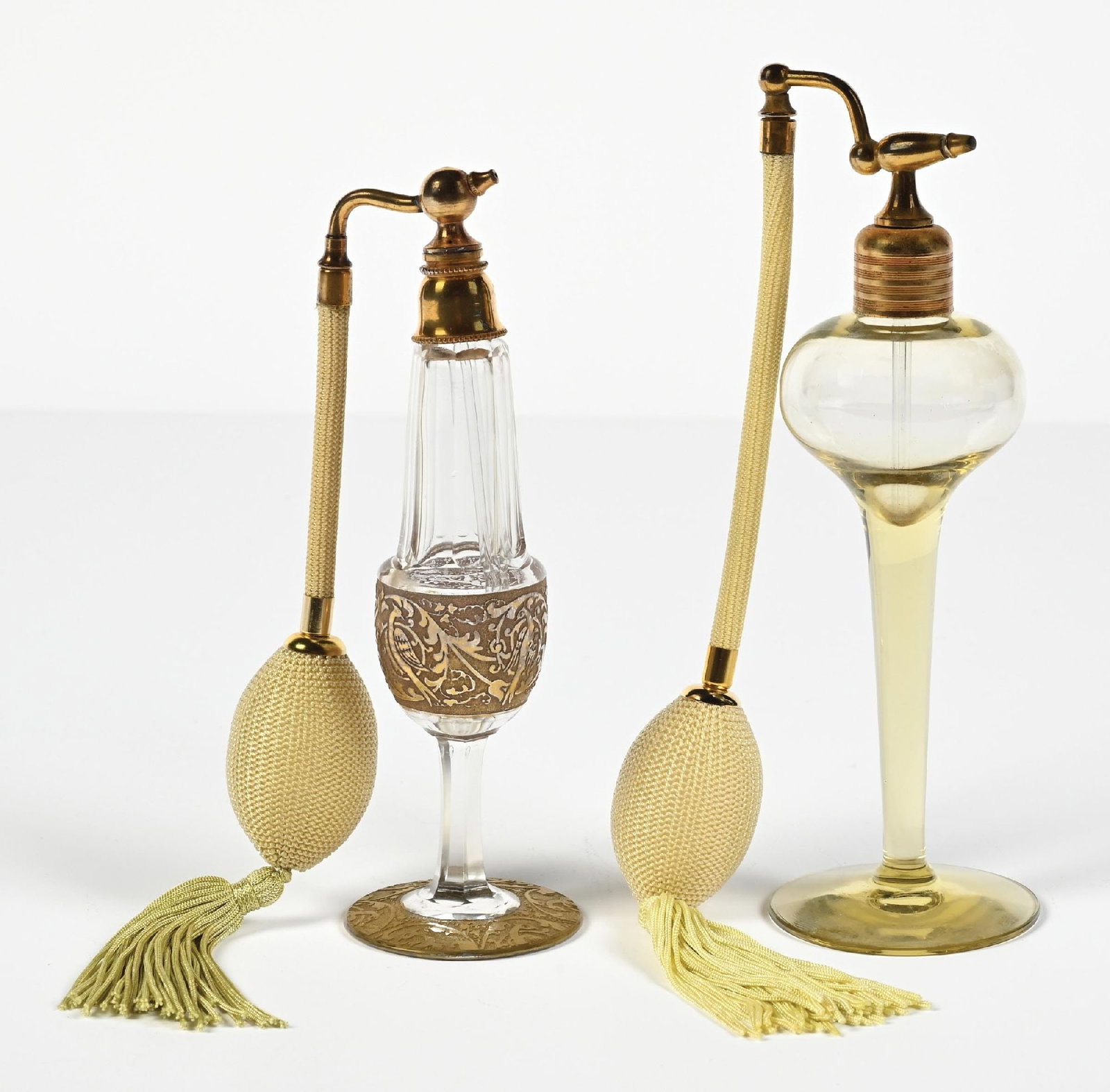 LOT OF 2: MOSER & DEVILBISS CLEAR/GOLD GILT & YELLOW GLASS PERFUMES: C. 1920s-1930s. An ornate Moser glass perfume atomizer with a gold-tone gilt pheasant and floral design featuring a tall, tapered glass body. The perfume has gold-toned hardware, yellow-green hose,