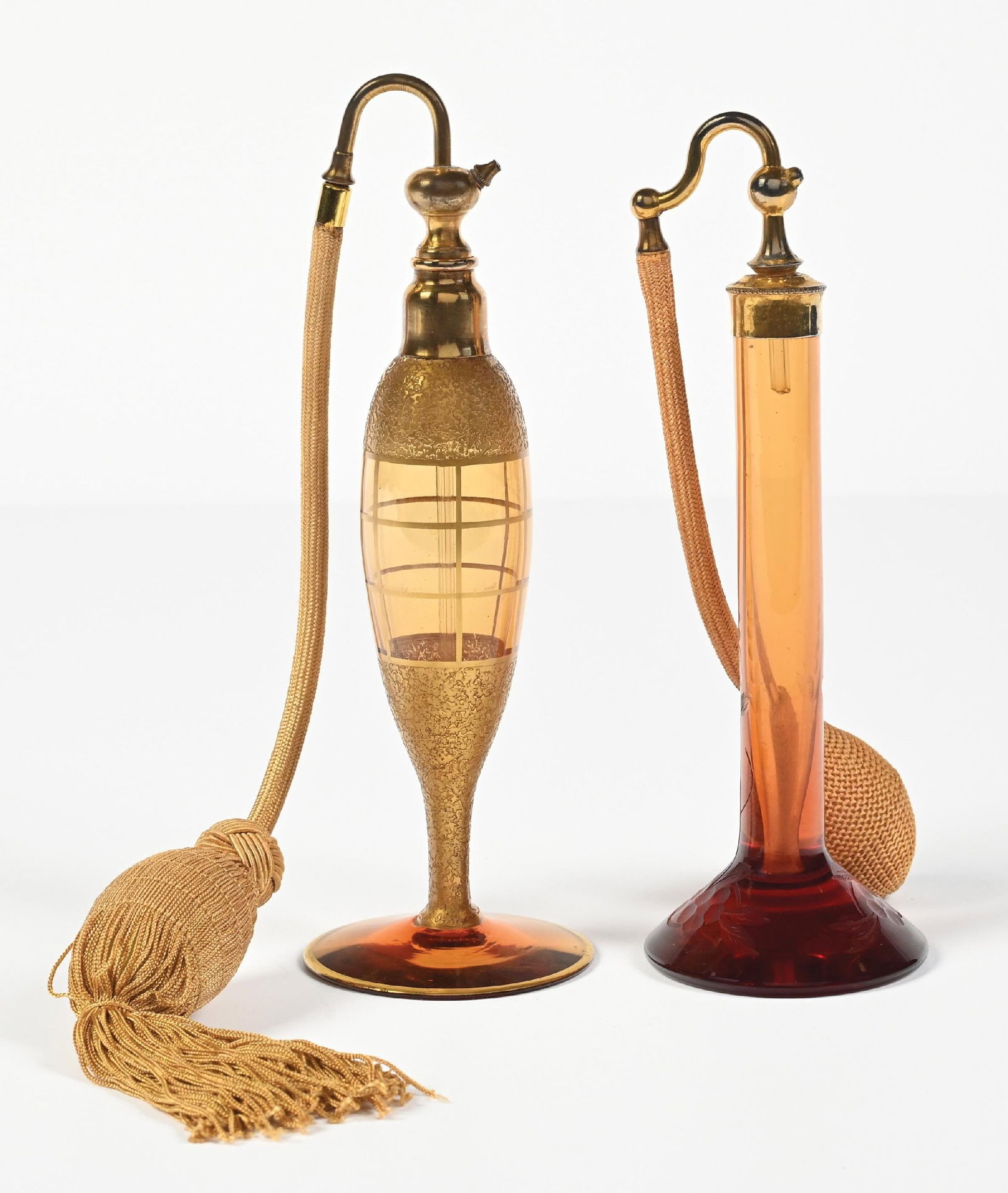 LOT OF 2: DEVILBISS AMBER & GOLD PERFUMES WITH ATOMIZERS: C. 1920s. (A) A cheerful DeVilbiss perfume atomizer with an amber body, an acid-gold applied geometric pattern, with patina/slight fading on the gold-toned hardware, a gold ornate functional hose, and
