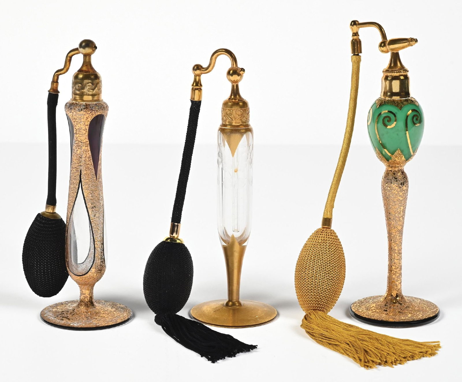 LOT OF 3: ART DECO DEVILBISS GOLD PERFUME ATOMIZERS: C. 1920s. (A) An attractive DeVilbiss perfume atomizer features a clear glass body with floral etchings, housed within a gold-toned base stem and topped with gold hardware, a black hose, and a functio