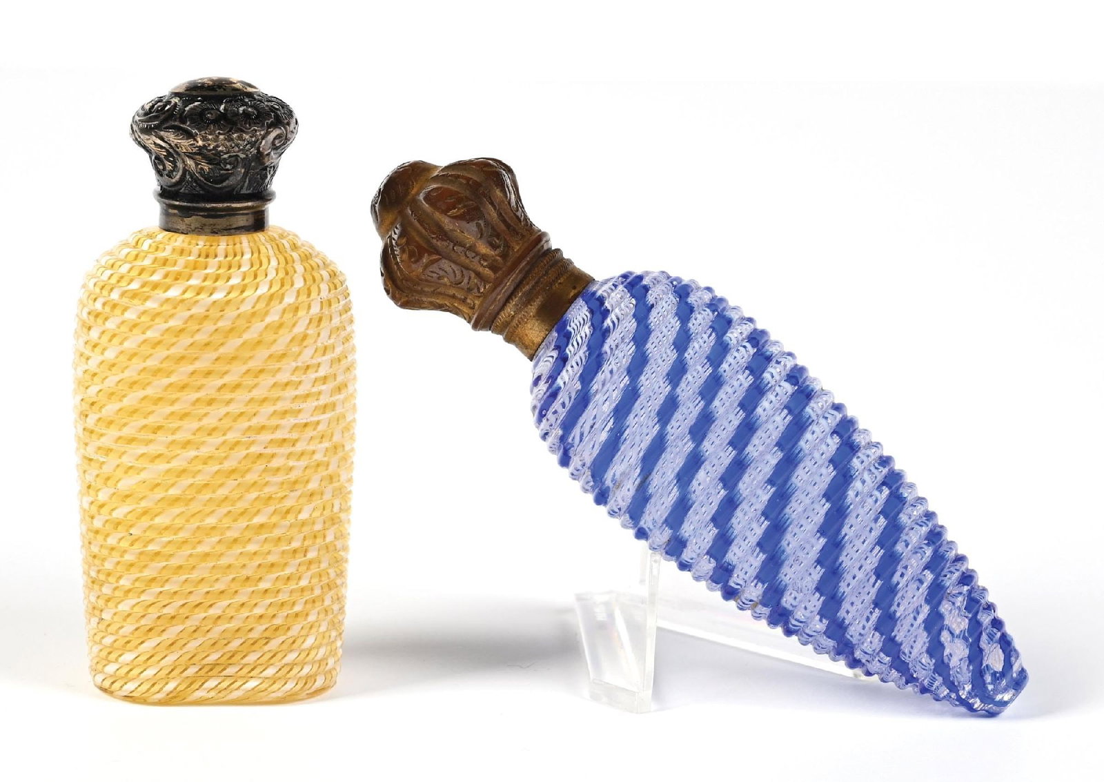 LOT OF 2: FRENCH LATTICINO GLASS PERFUME BOTTLES: C. 1800s. A collection of two beautiful yellow and blue latticino (filigrana) glass perfumes with ornate metal caps. The yellow perfume has a minor crazing at the base. Both perfumes are in beautiful