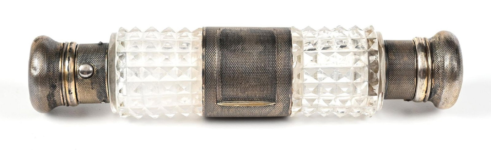 CRYSTAL & METAL PERFUME BOTTLE: C. 1800s. A gorgeous diamond-cut glass double-sided perfume vinaigrette. The perfume features a cylindrical body made of clear-cut glass with a faceted diamond pattern. Each end is adorned with silver