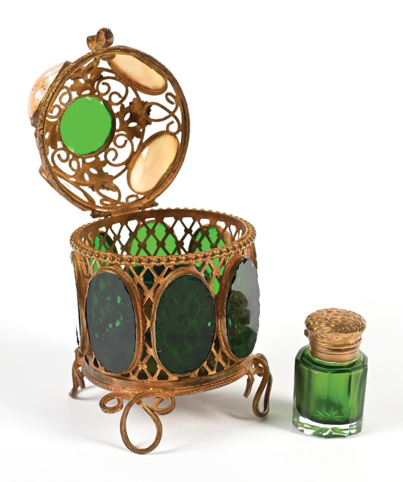 MOTHER OF PEARL EGG AND GREEN GLASS PERFUME CADDY AND PERFUME: C. 1800s. A Palais Royal mother-of-pearl and green glass perfume casket in a cylindrical shape, adorned on a four-footed ornate brass mount featuring a decorative foliage pattern, making the casket ap