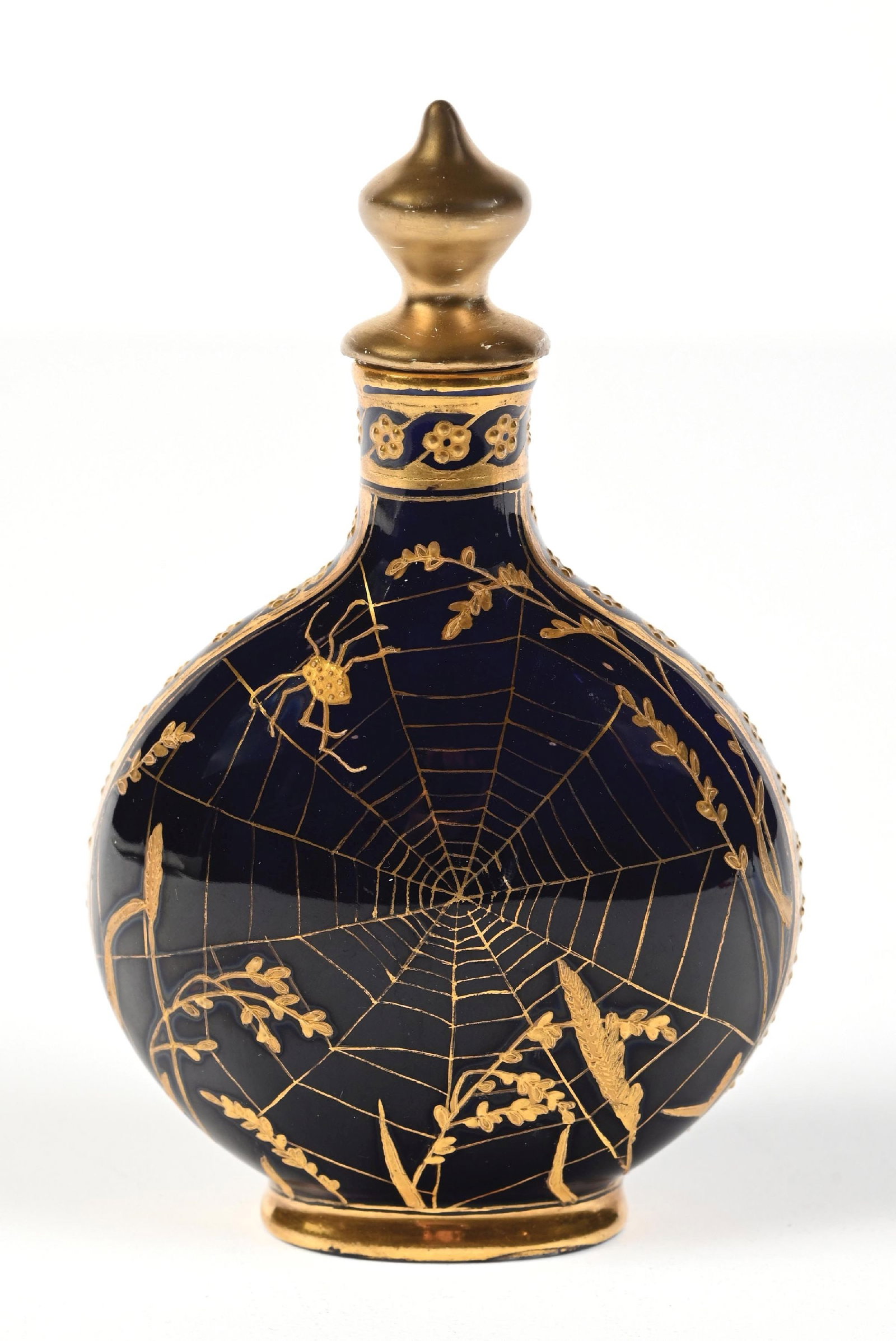 COALPORT PERFUME BOTTLE WITH SPIDER WEB MOTIF: C. 1800s. A signed Coalport porcelain perfume bottle featuring a cobalt blue exterior with gold-toned enamel spiderweb and floral patterning on top, in great condition. 3" x 5". Condition: 200 Dimensi