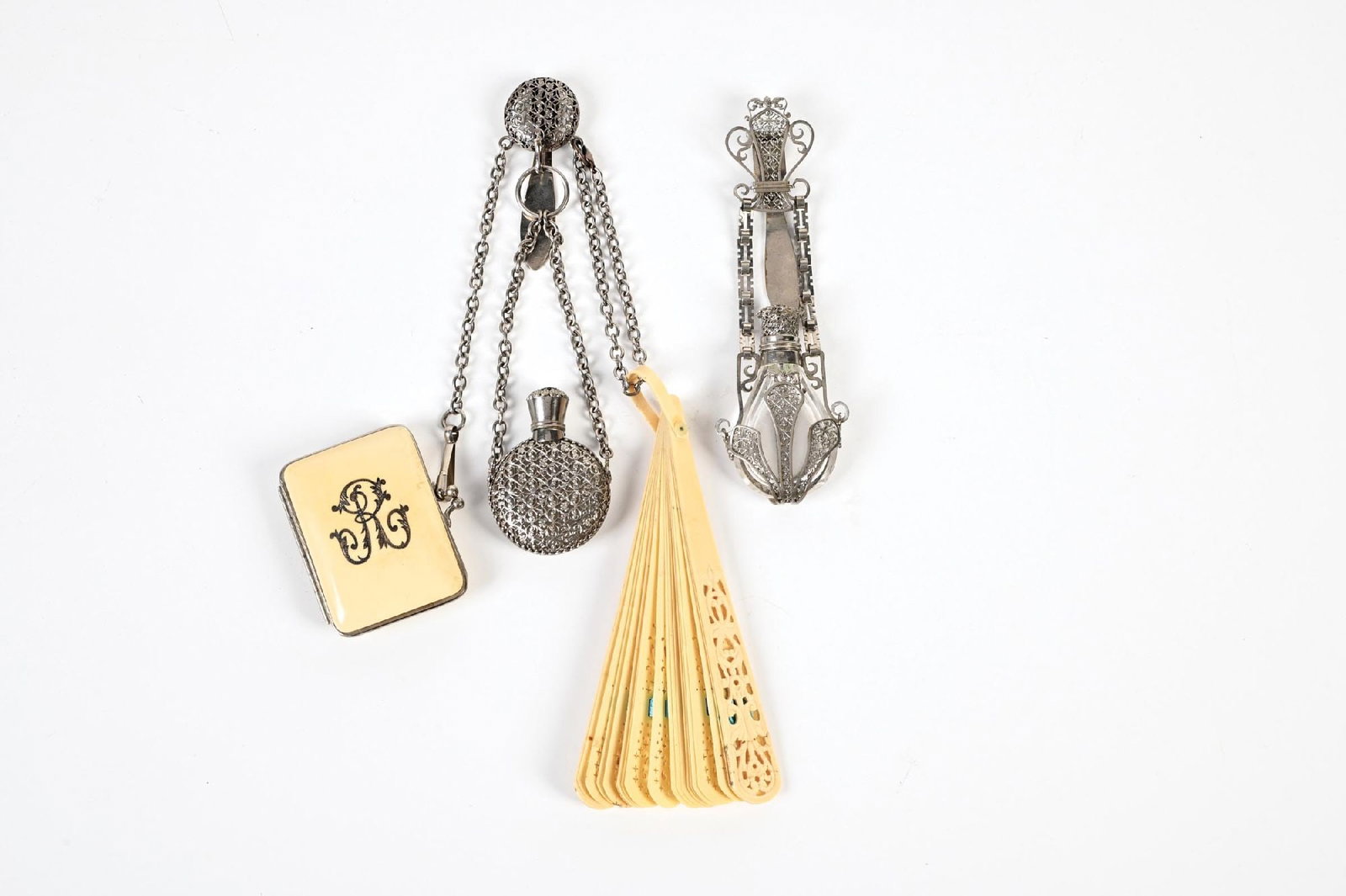 LOT OF 2: FAN & SCENT BOTTLE CHATELAINES: C. 1800s. (A) A fantastic floral celluloid fan, a celluloid coin purse featuring an “R” initial, and two cut glass silver filigree-overlaid perfumes and chains. All have a natural patina a