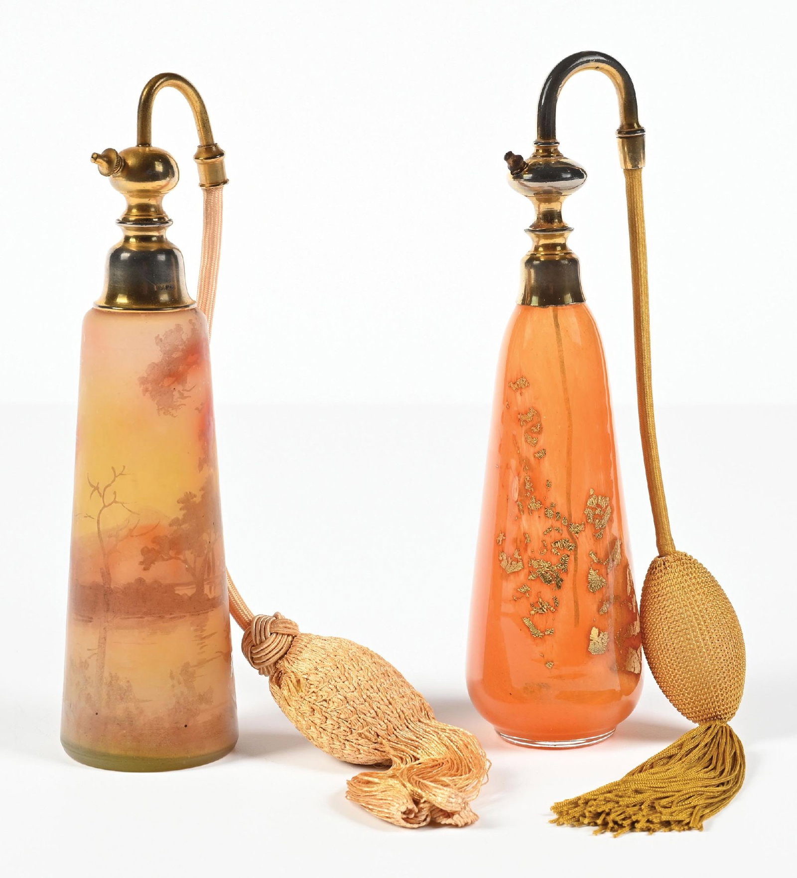 LOT OF 2: ORANGE GLASS PERFUME ATOMIZERS: C. 1900s. (A) A striking Marcel Franck perfume, signed Peynaud, with molten glass scene in sunset oranges and yellows featuring trees, a river, and a boat, it is a gorgeous scene. The collar is stampe