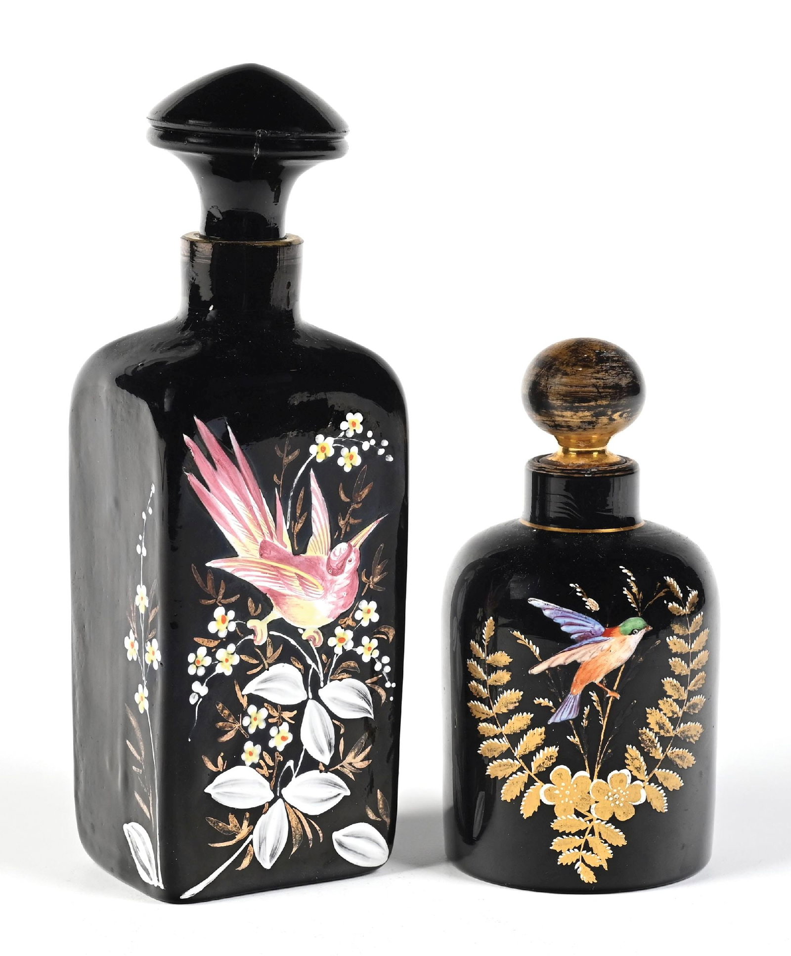 LOT OF 2: BLACK HAND-PAINTED BIRD MOTIF PERFUME BOTTLES: C. 1900s. (A) A gorgeous, large, thick black art glass perfume featuring hand-painted enamel decoration of a bird and flowers in white and pink with a matching stopper and faded gold accents. The bott