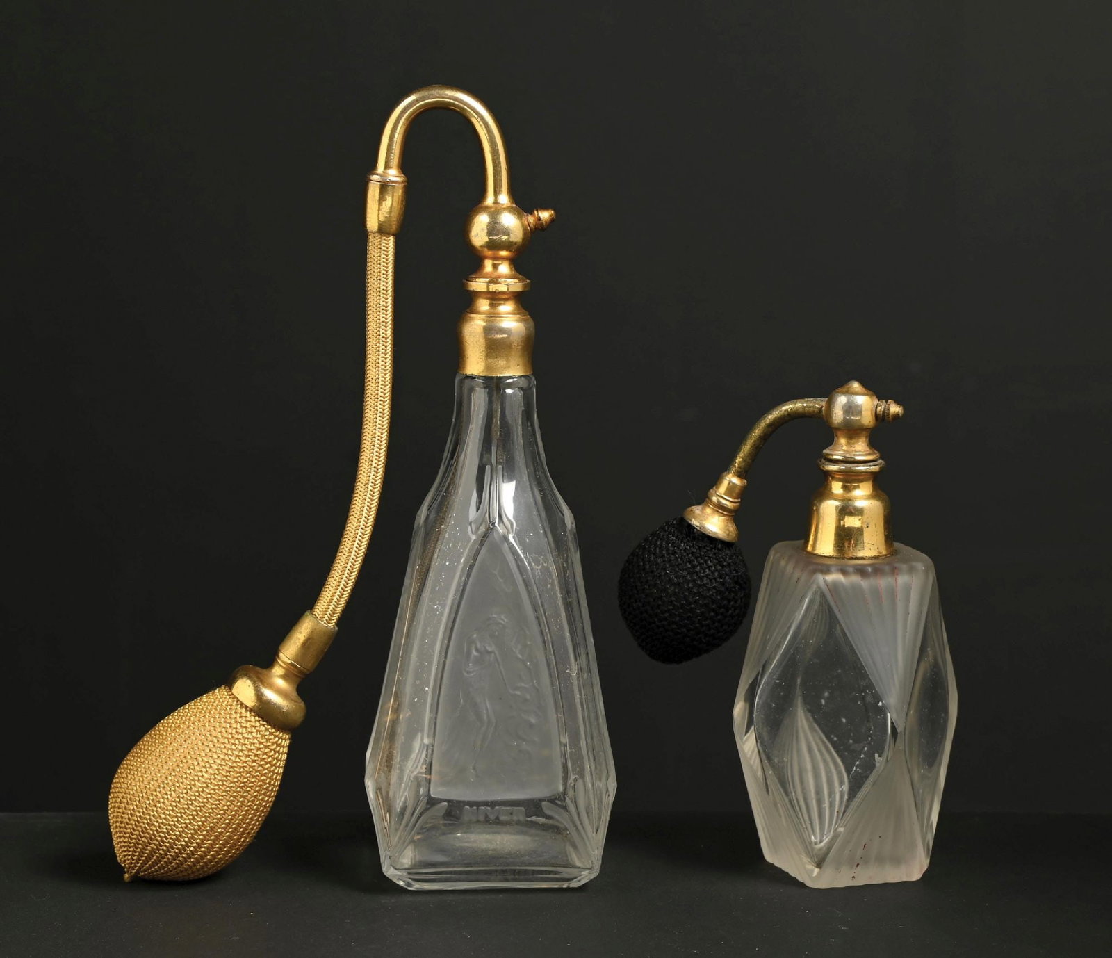 LOT OF 2: ART DECO FROSTED GLASS PERFUMES WITH ATOMIZERS: C. 1900s. (A) A pretty French faceted frosted glass perfume atomizer with a triangular panel featuring a figural nudes depicting the four seasons, with a gold-tone metal mechanism and a gold fabric fu