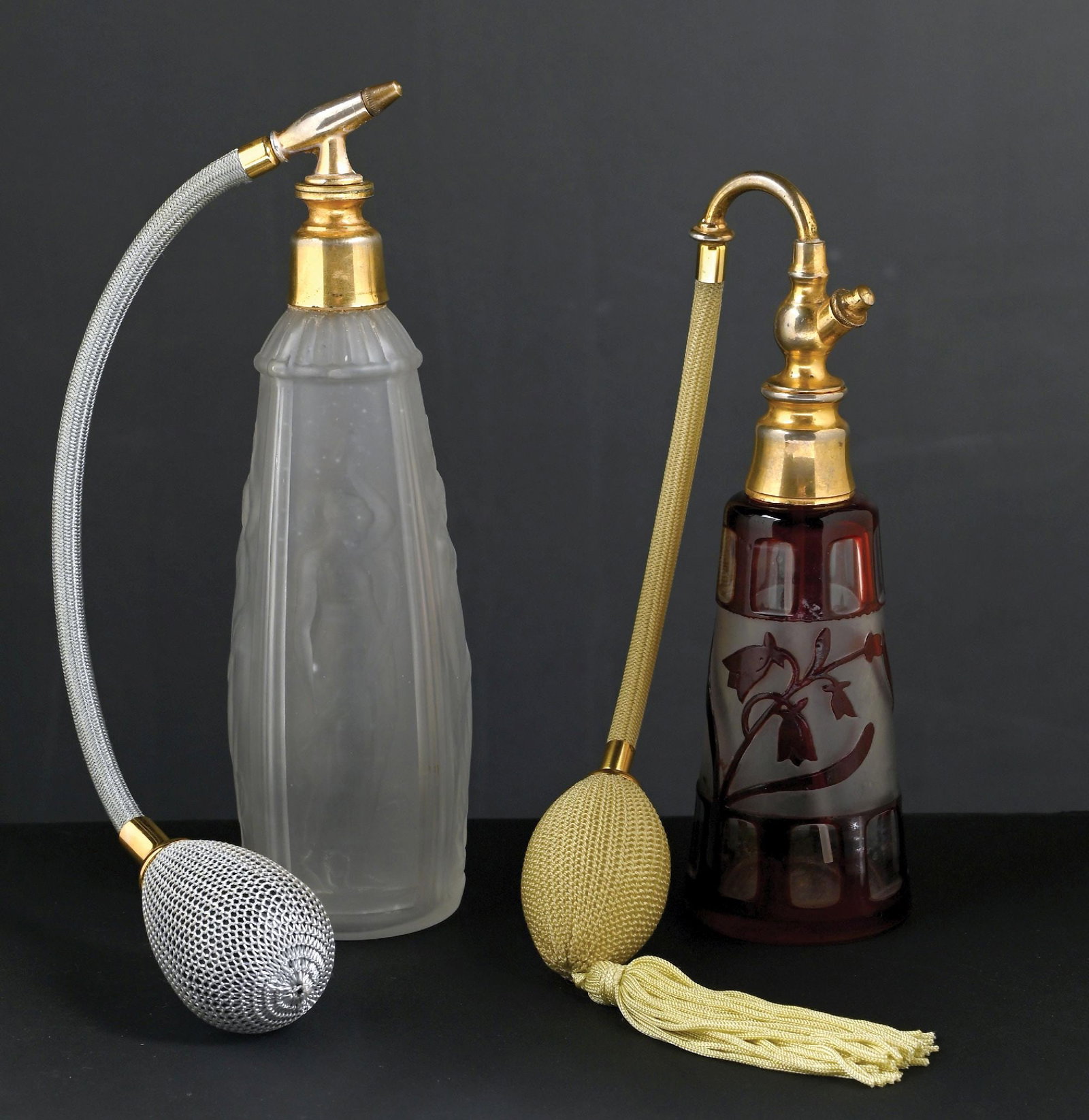 LOT OF 2: ART DECO FROSTED GLASS & CAMEO ETCHED GLASS PERFUME ATOMIZERS: C. 1900s. (A) A gorgeous frosted glass perfume atomizer, the bottle features nude figural reliefs. The perfume is equipped with gold-toned metal hardware, a gray hose, and a functional puff. In great 