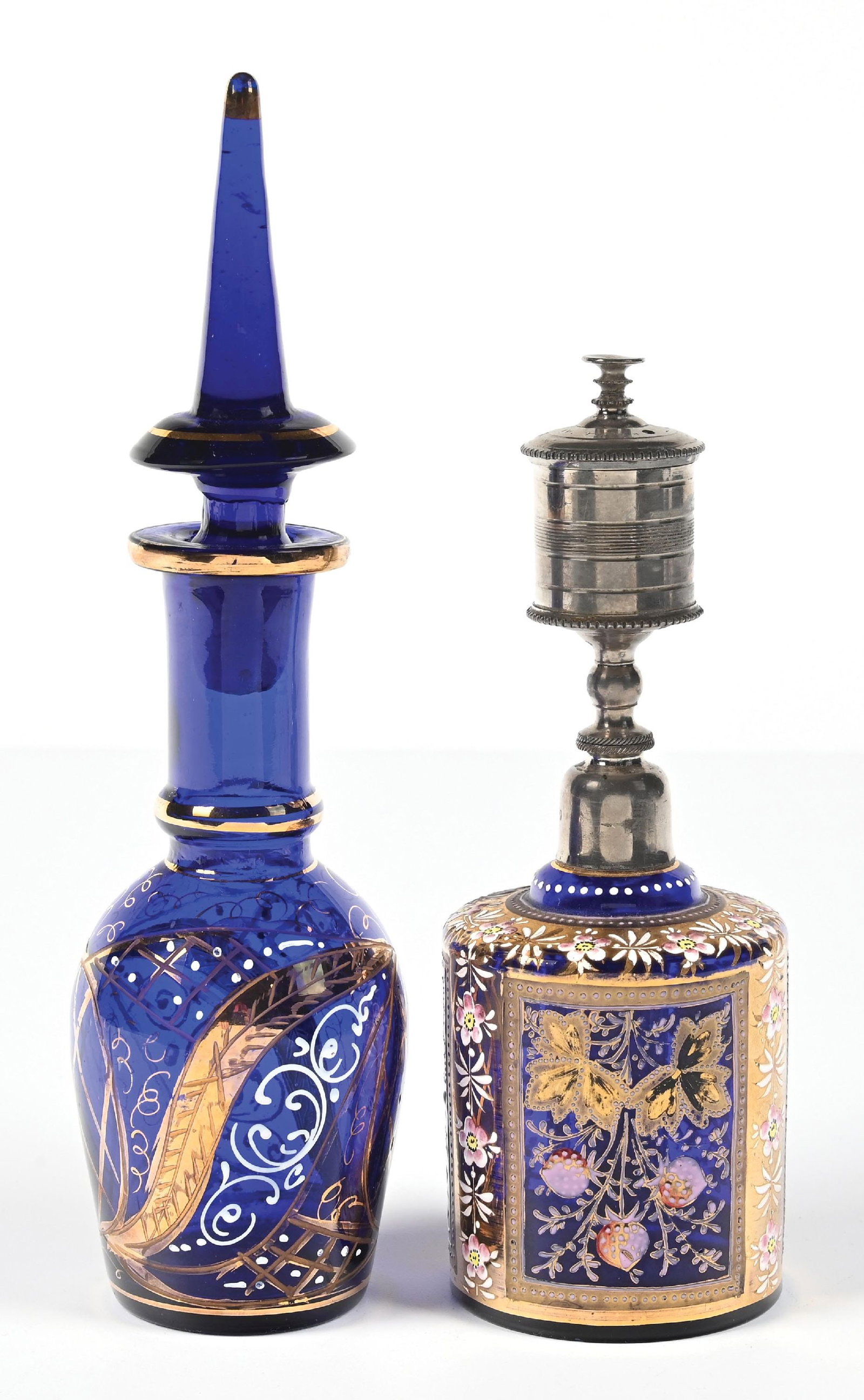 LOT OF 2: ORNATE COBALT PERFUMES WITH GOLD & FLORAL ENAMEL PATTERNS: C. 1900s. (A) An attractive Bohemian Persian cobalt blue hand-painted enamel perfume featuring a spire stopper and adorned with gold and white scrollwork and floral motifs. The body of the glass and t