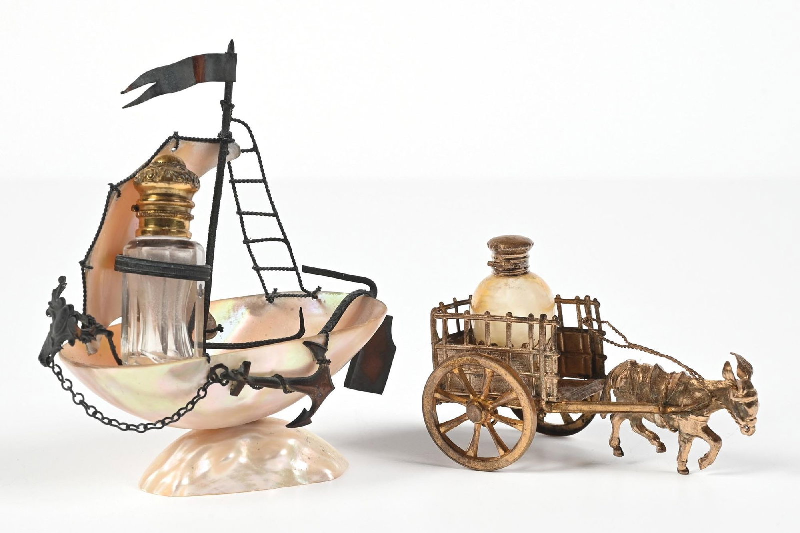 LOT OF 2: DONKEY DRAWN CARRIAGE & MOTHER OF PEARL SAILBOAT PERFUME BOTTLE STANDS: C. 1800s. (A) A beautiful mother-of-pearl shell perfume ship. (B) A fantastic Palais Royal donkey pulled brass perfume vanity set, with perfume in the shape reminiscent of a vintage Christmas tree bul