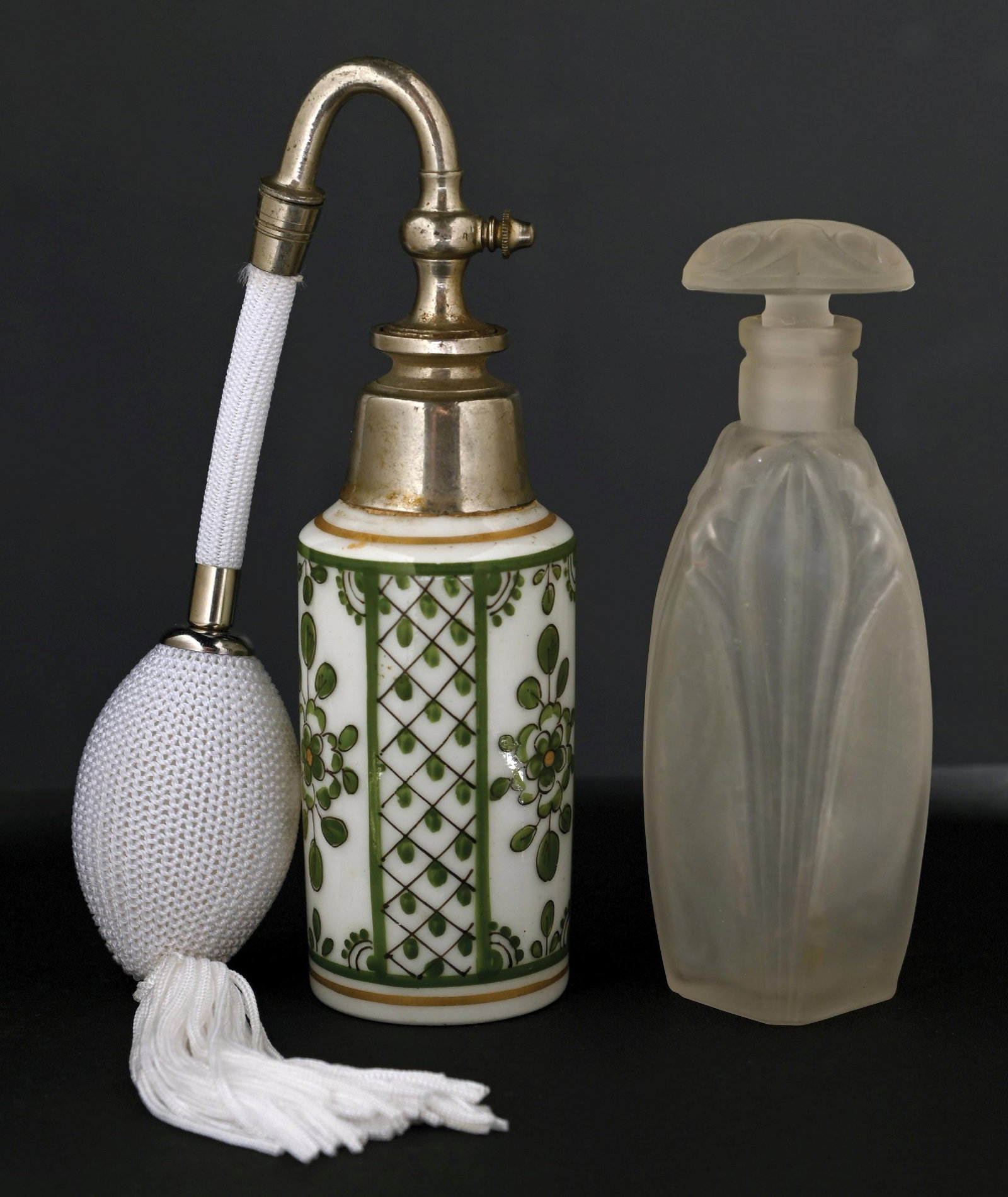 LOT OF 2: GREEN FLORAL & FROSTED GLASS PERFUME BOTTLES: C. 1900. (A) A French porcelain perfume atomizer featuring a green floral and geometric pattern with a silver-toned metal top, with a functional white squeeze puff with tassels. (B) A beautiful froste