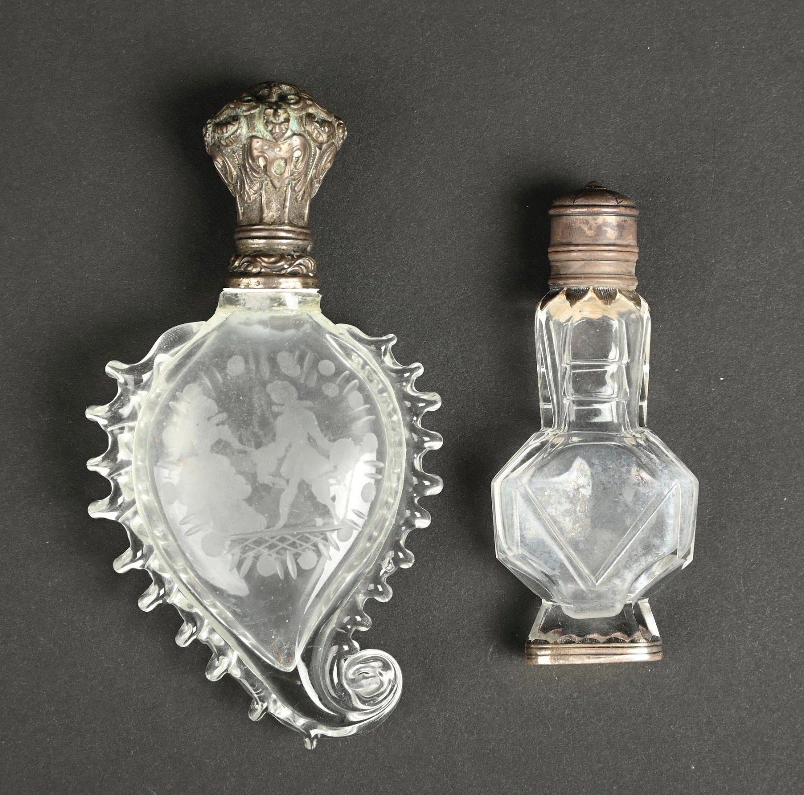 LOT OF 2: CLEAR CUT GLASS MINIATURE PERFUME BOTTLES: C. 1800s. A collection of two lovely clear glass perfumes with silver lids. The perfume resembling a leaf appears to have a repair around the collar, otherwise the perfumes are in good condition. Larg