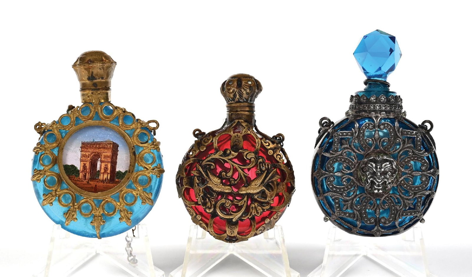 LOT OF 3: GLASS GILDED PERFUME BOTTLES: C. 1800s. A collection of high-end traveling perfume Chatelaines in a Napoleon III style, with each piece being encased in gilded metals. One of the perfumes stands out as a Palais Royal scent bottle 