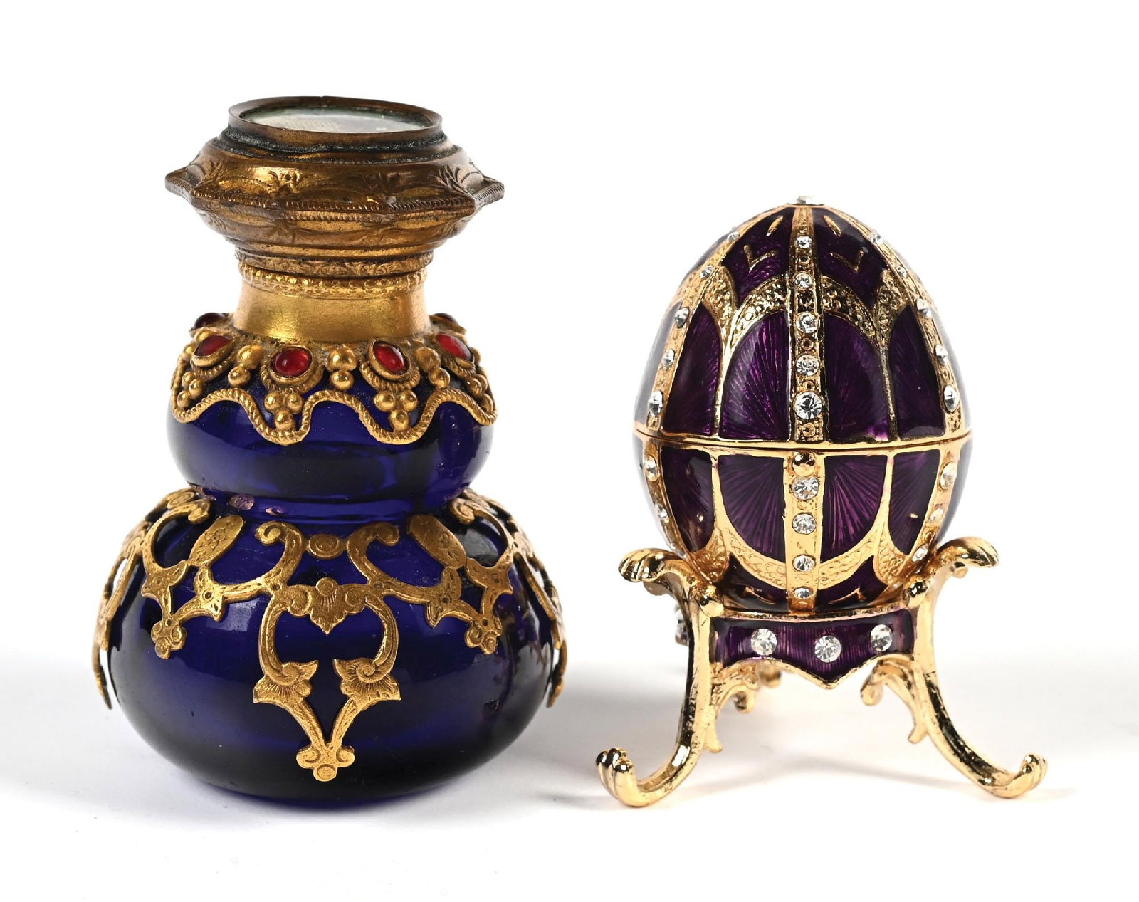 LOT OF 2: SMALL ORNATE BEJEWELED PERFUMES: C. 1800s. (A) A purple egg-shaped perfume/trinket jar, highly jeweled with a stand and yellow enamel interior, in great condition. (B) A Palais Royal cobalt blue bottle with a brass overlay and red je